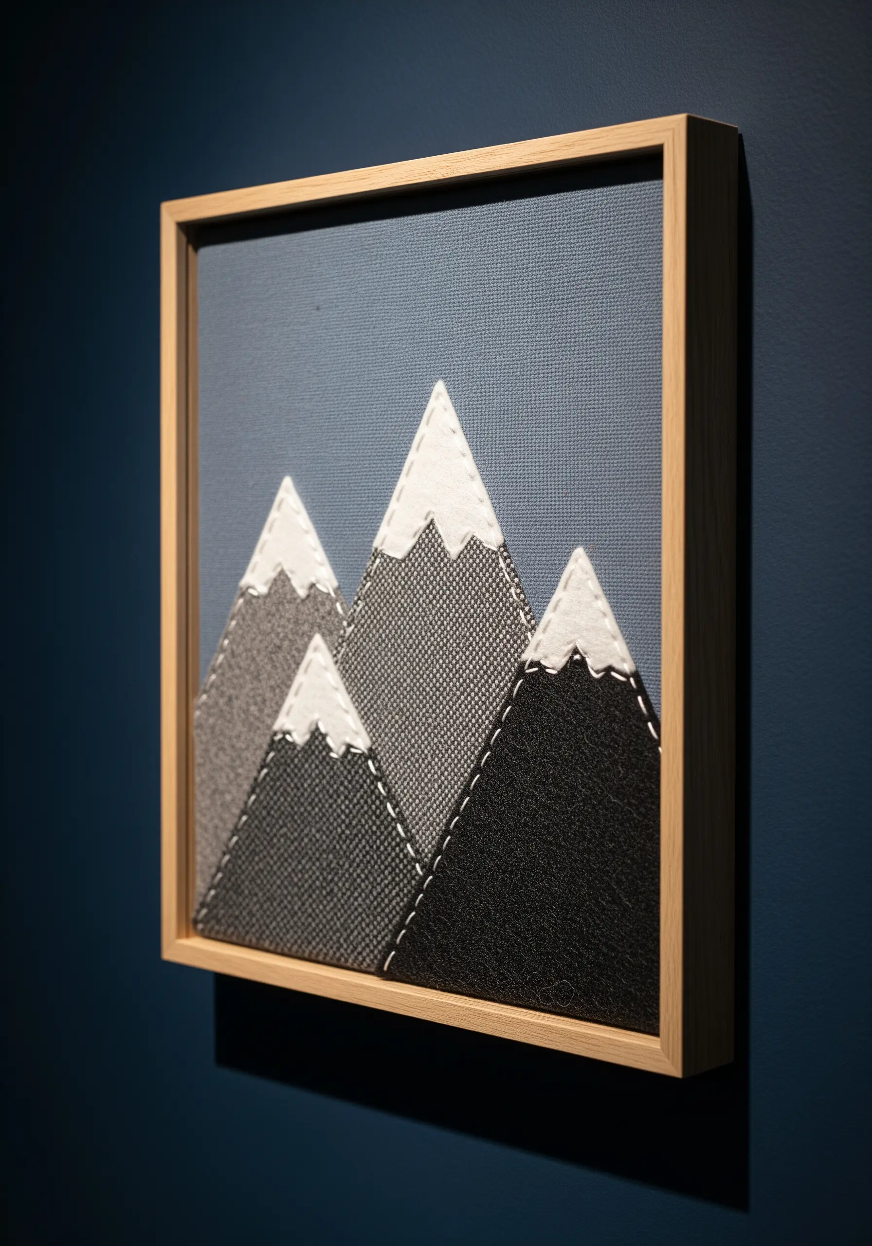 Framed felt appliqué mountain range with visible white running stitches for detail.