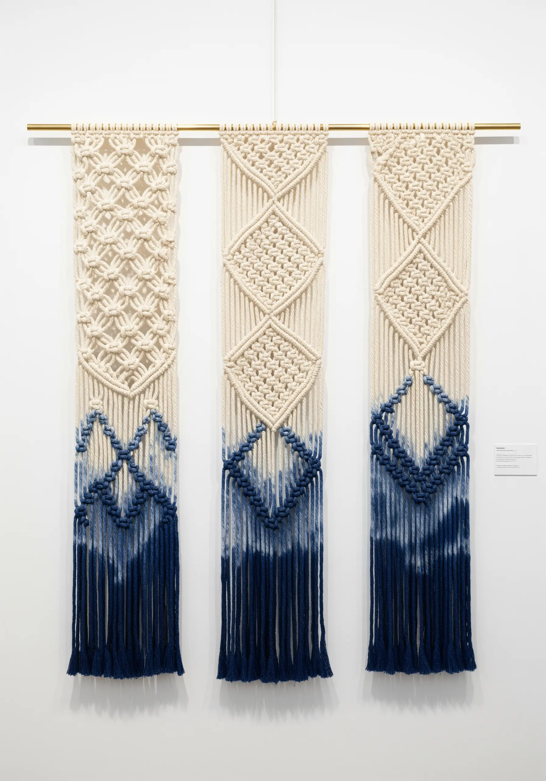 Three macrame panels with intricate knots at the top and dip-dyed indigo tips