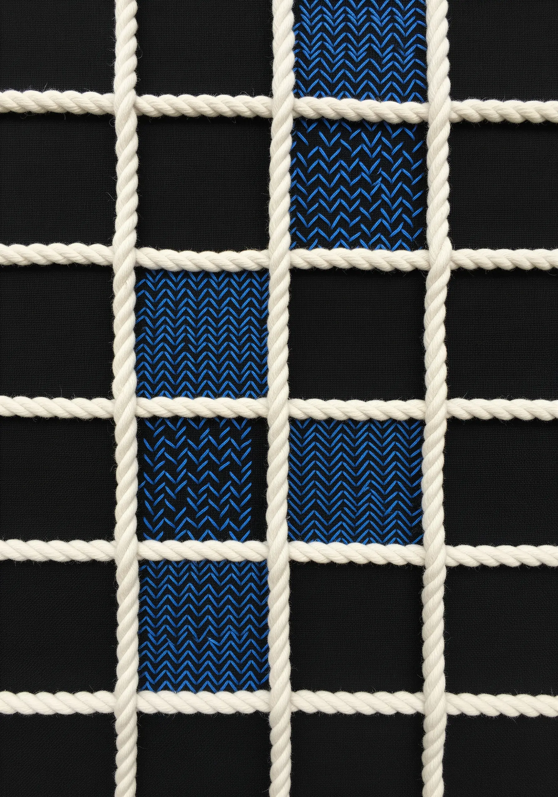 A white rope grid couched over a black background with blue herringbone stitch patterns.