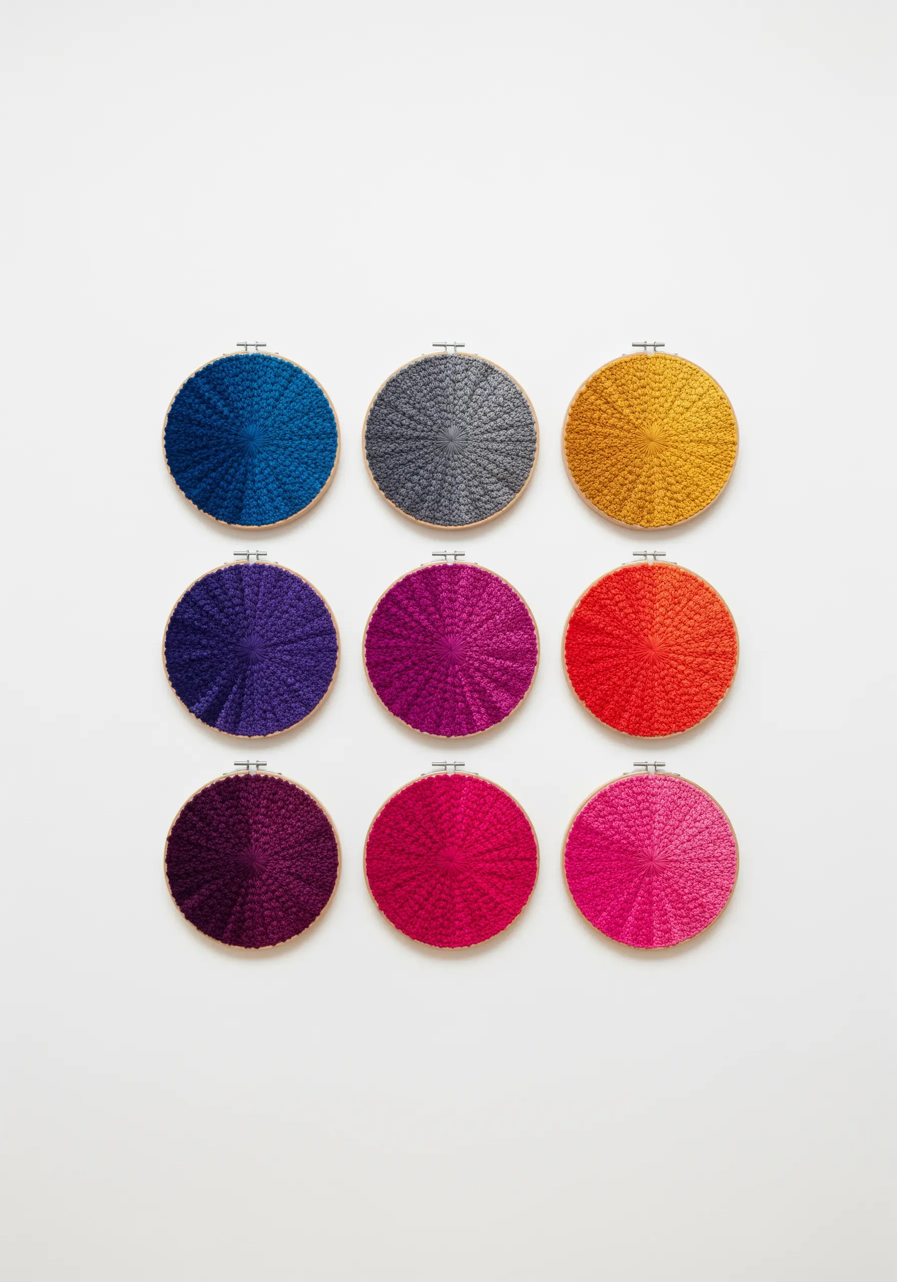 A grid of nine embroidery hoops, each filled with a dense texture of a single color.