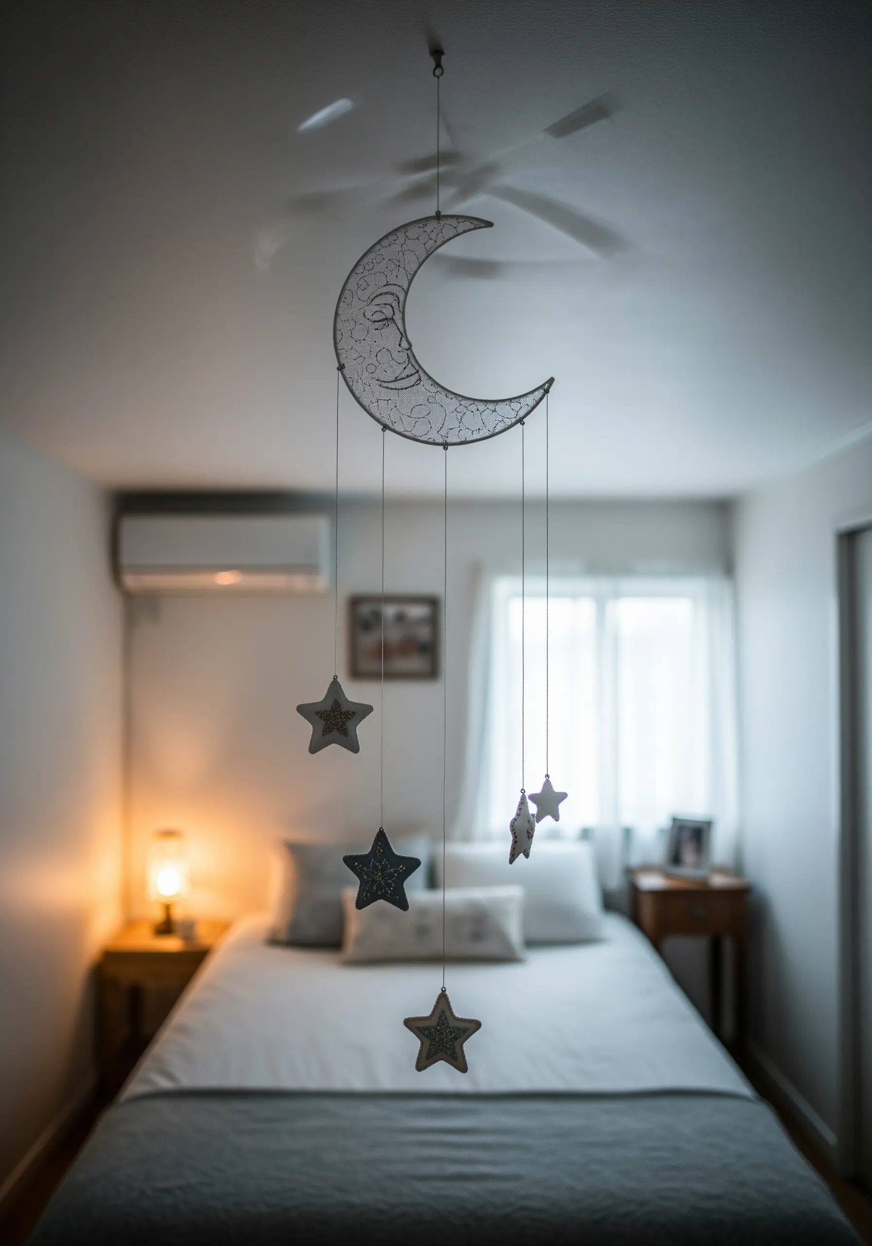 A delicate mobile made of a wire-wrapped crescent moon with smaller embroidered stars hanging below.