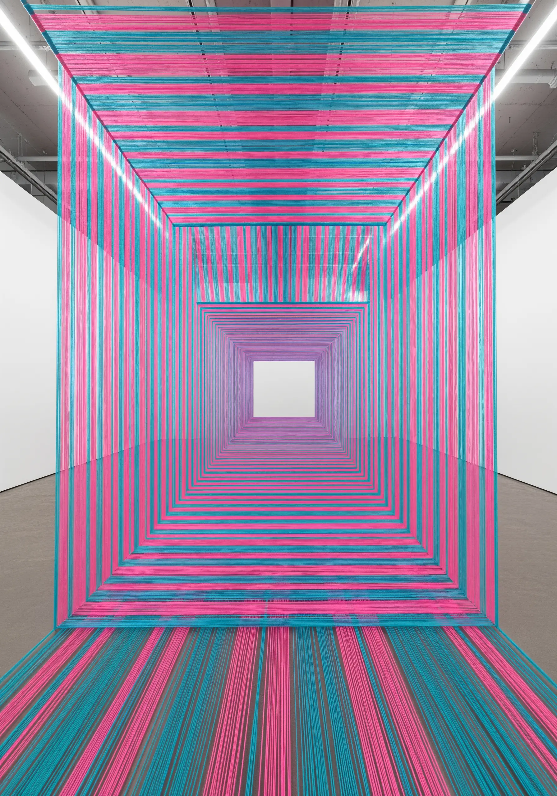 An installation of pink and teal threads forming a receding square tunnel, creating an optical illusion.
