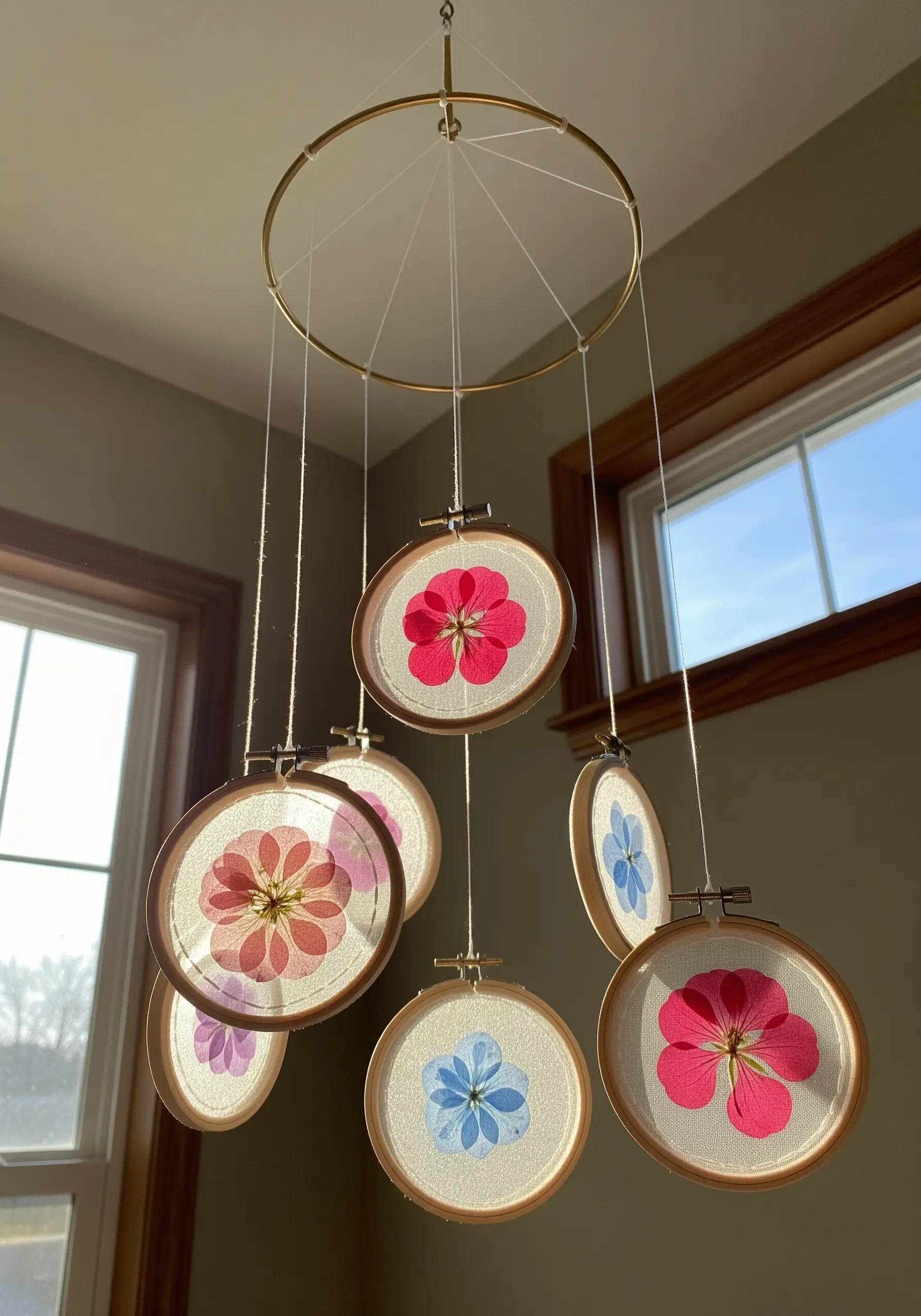 A nursery mobile made from small embroidery hoops with pressed flowers on sheer fabric.