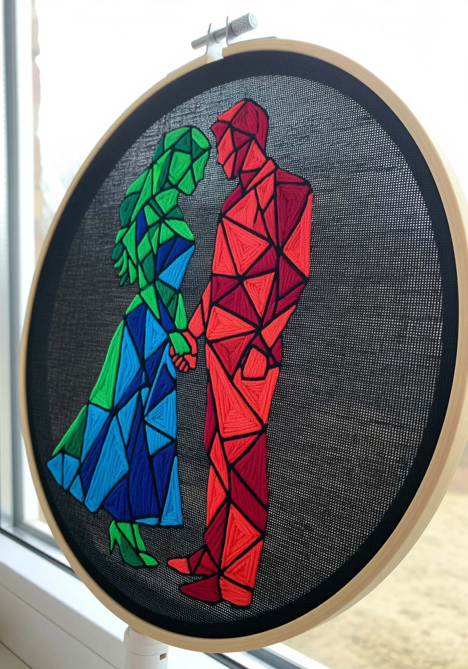 A couple silhouette filled with geometric shapes in red, green, and blue satin stitch.
