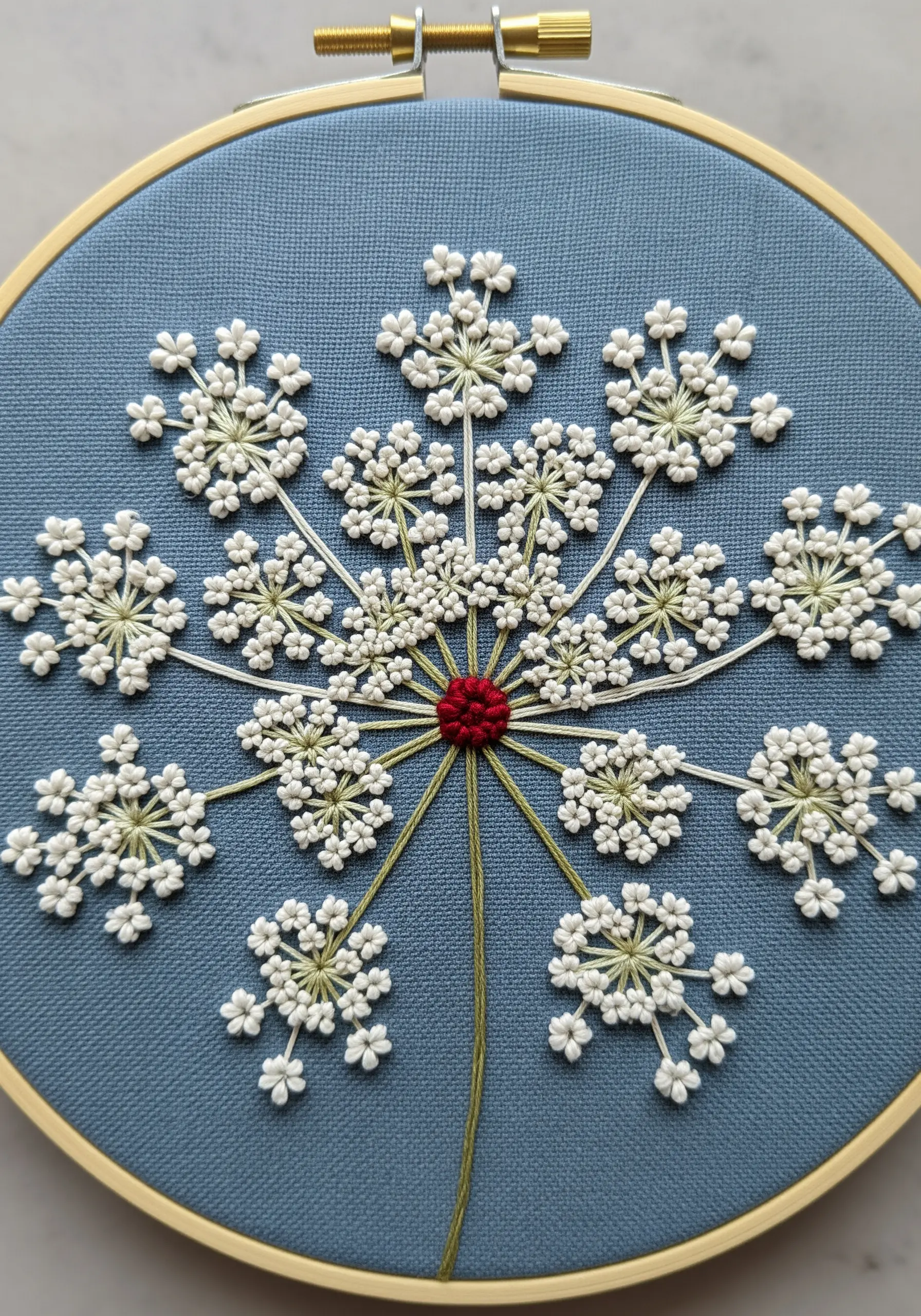 A large Queen Anne's Lace flower head embroidered on blue fabric