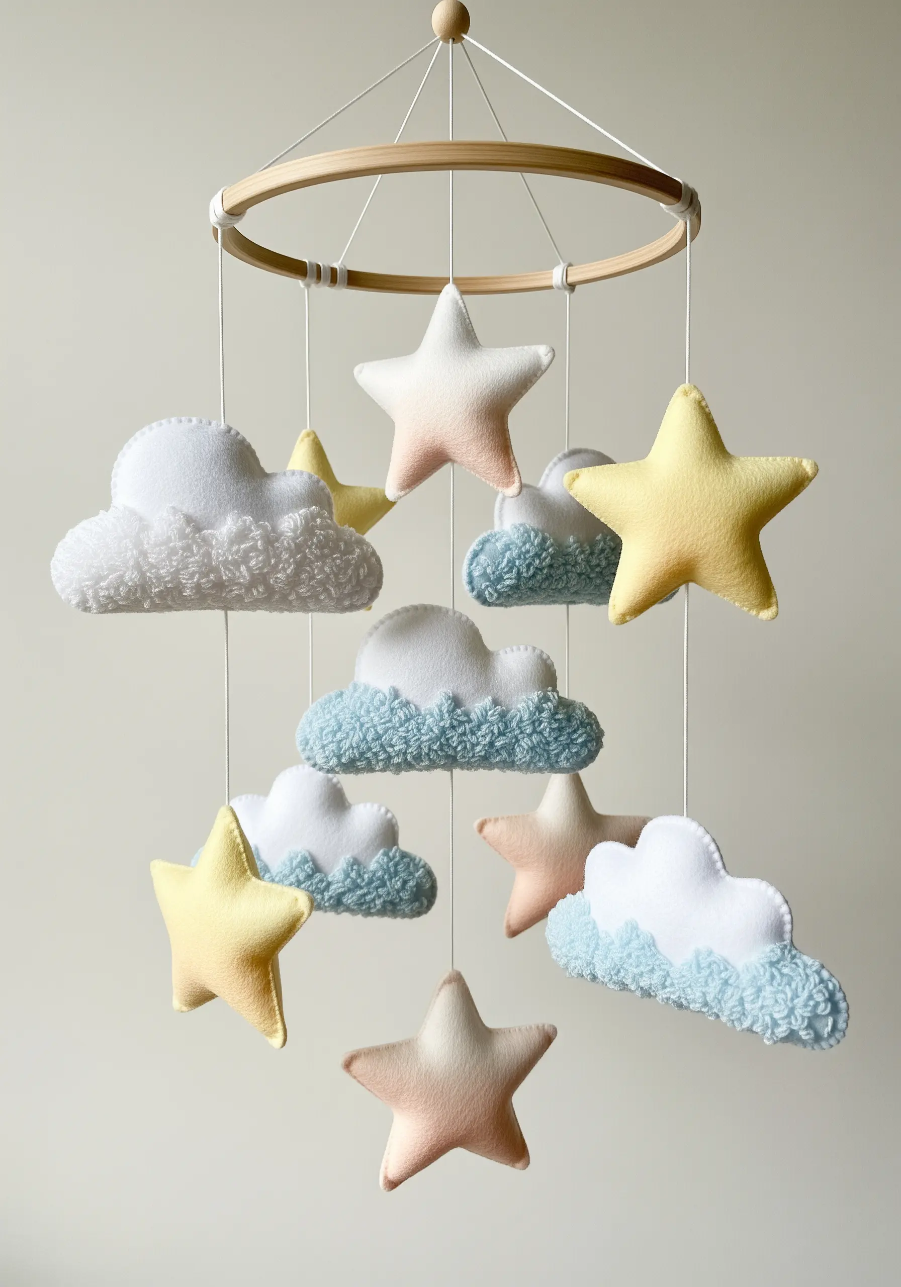 A nursery mobile with pastel felt stars and textured, embroidered clouds.