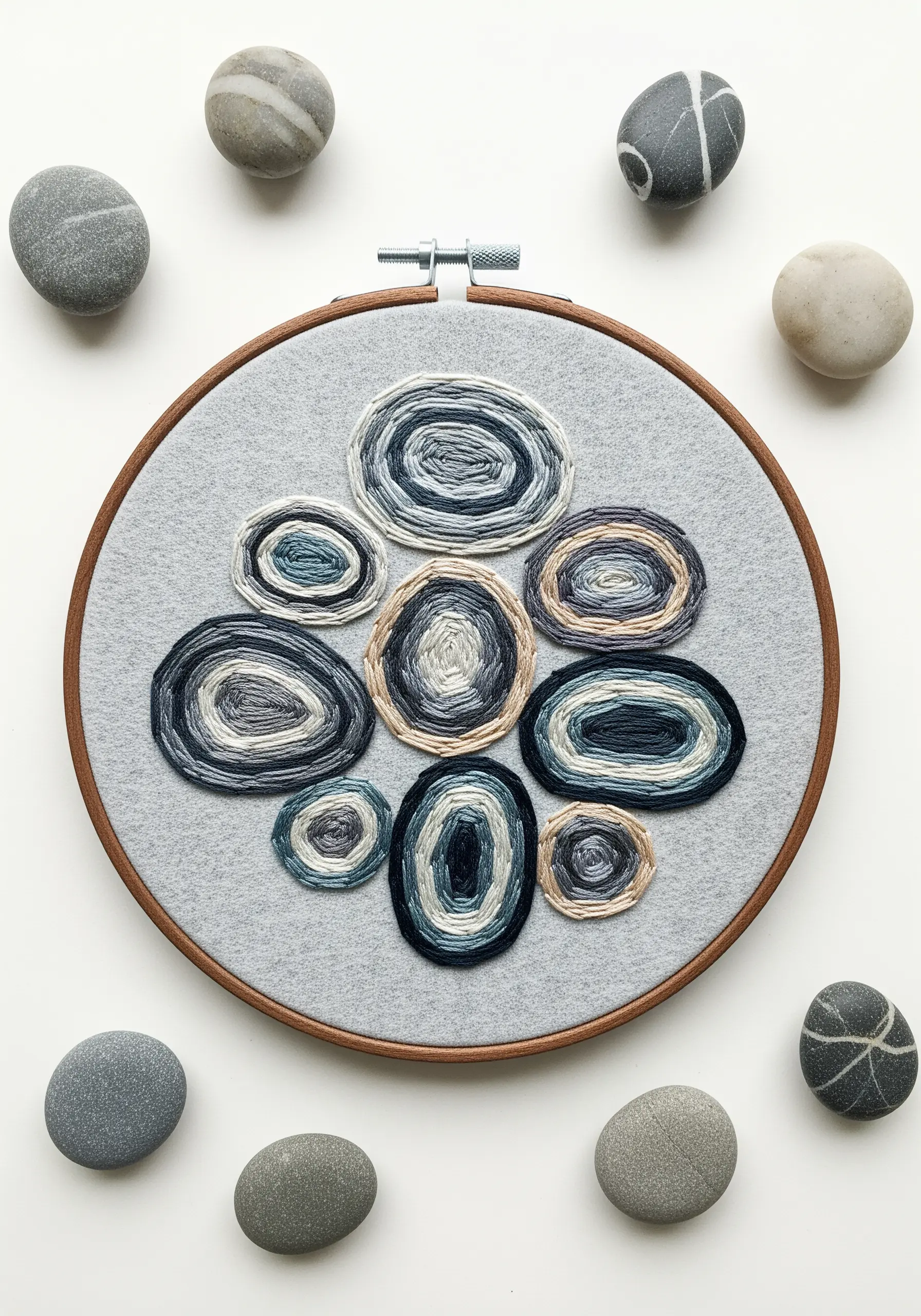 Embroidered stones with concentric rings of blue and grey thread.