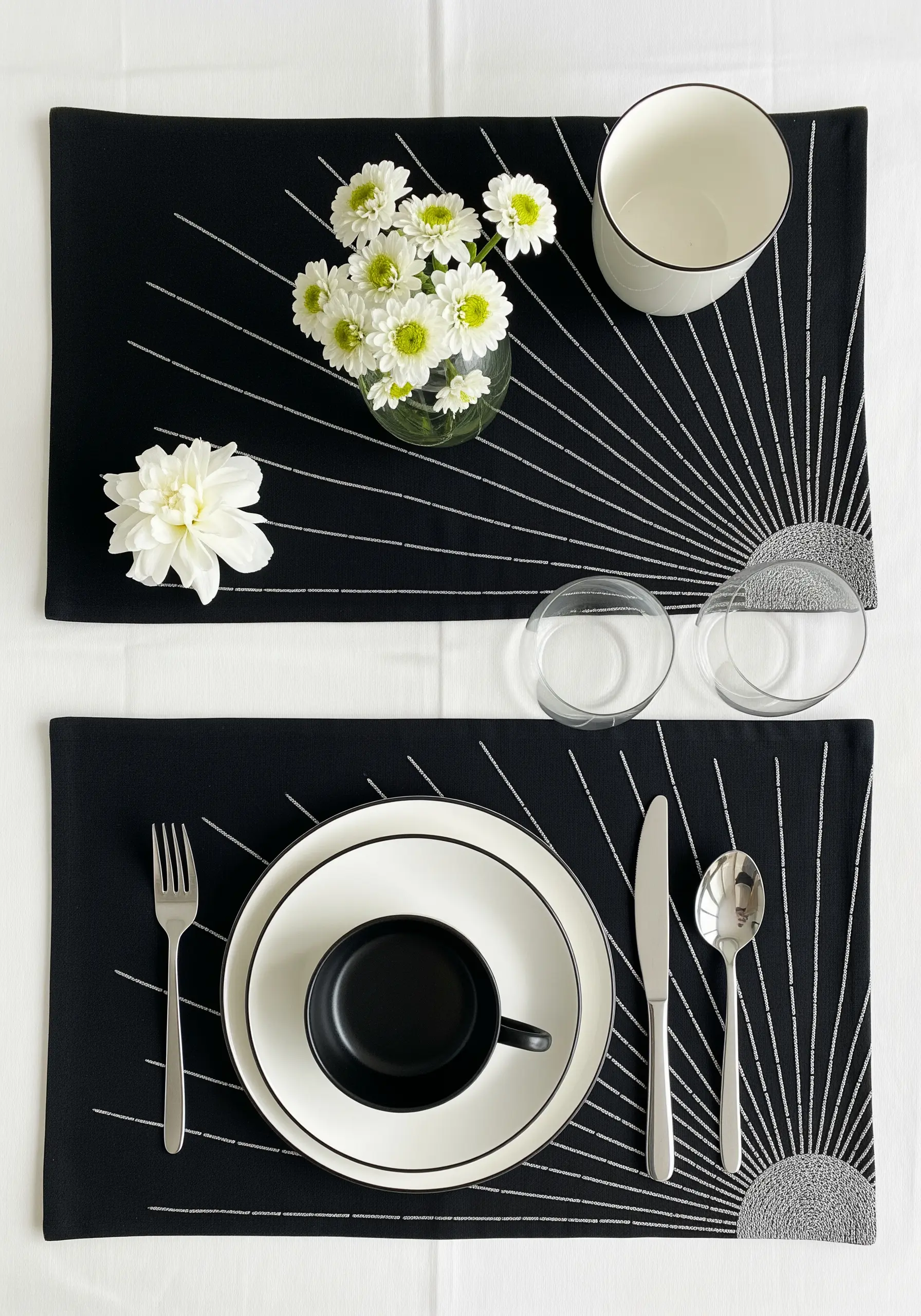 Black placemats with a graphic sunburst motif embroidered in white or silver metallic thread.