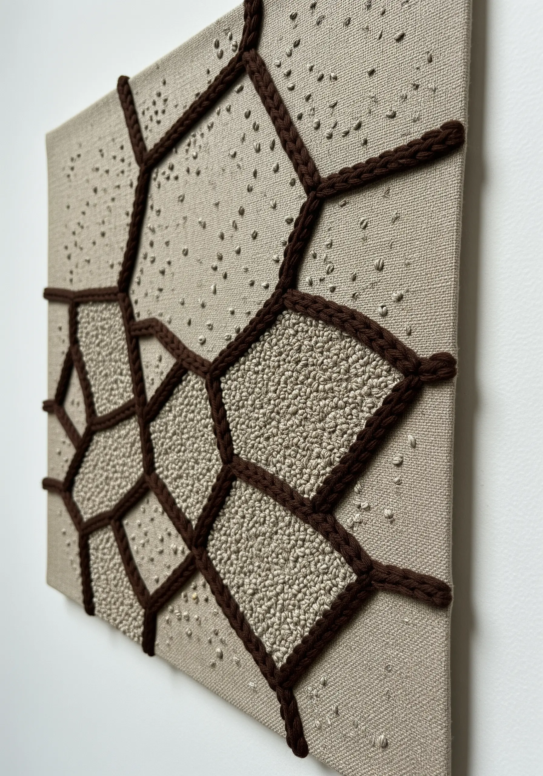 Canvas with a geometric pattern outlined in brown cord and filled with French knots.