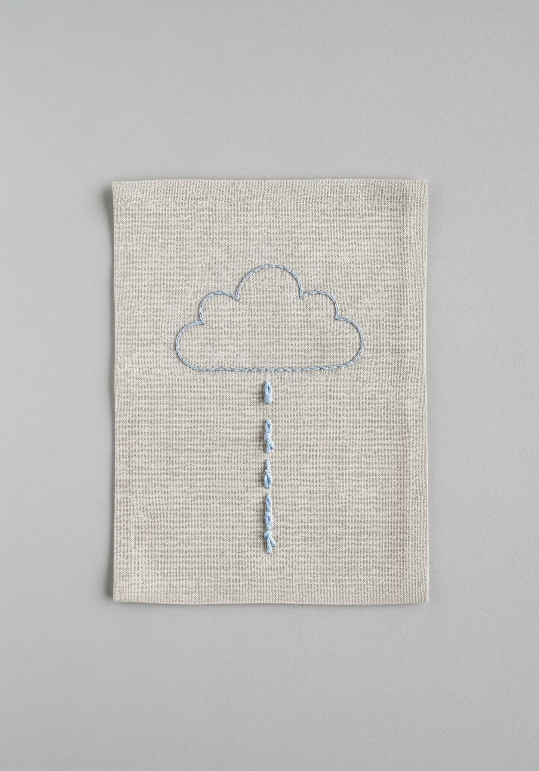 Minimalist cloud outline with the word 'luck' stitched as falling raindrops.