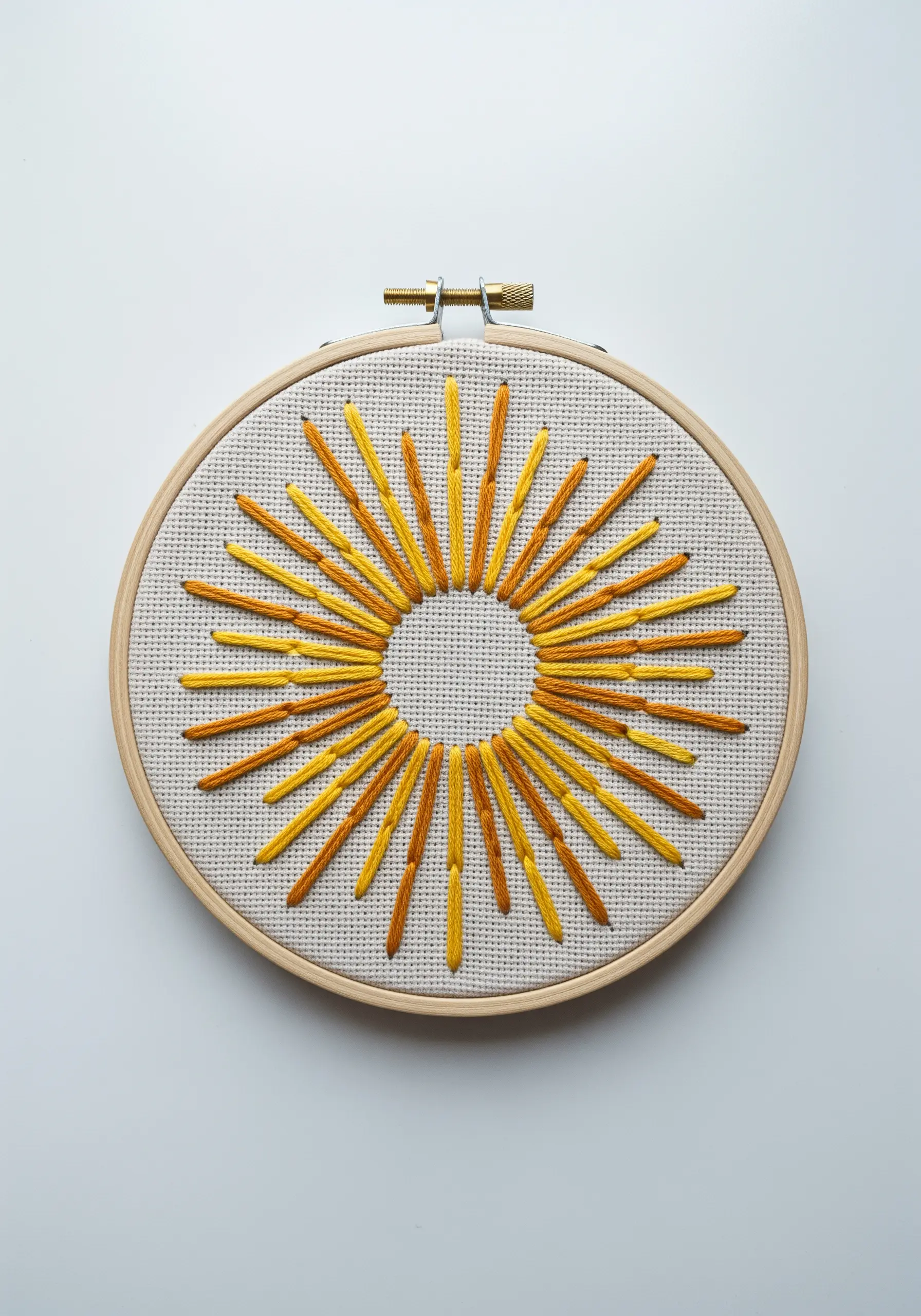 Abstract sunburst embroidery with radiating yellow and gold straight stitches of varying lengths.