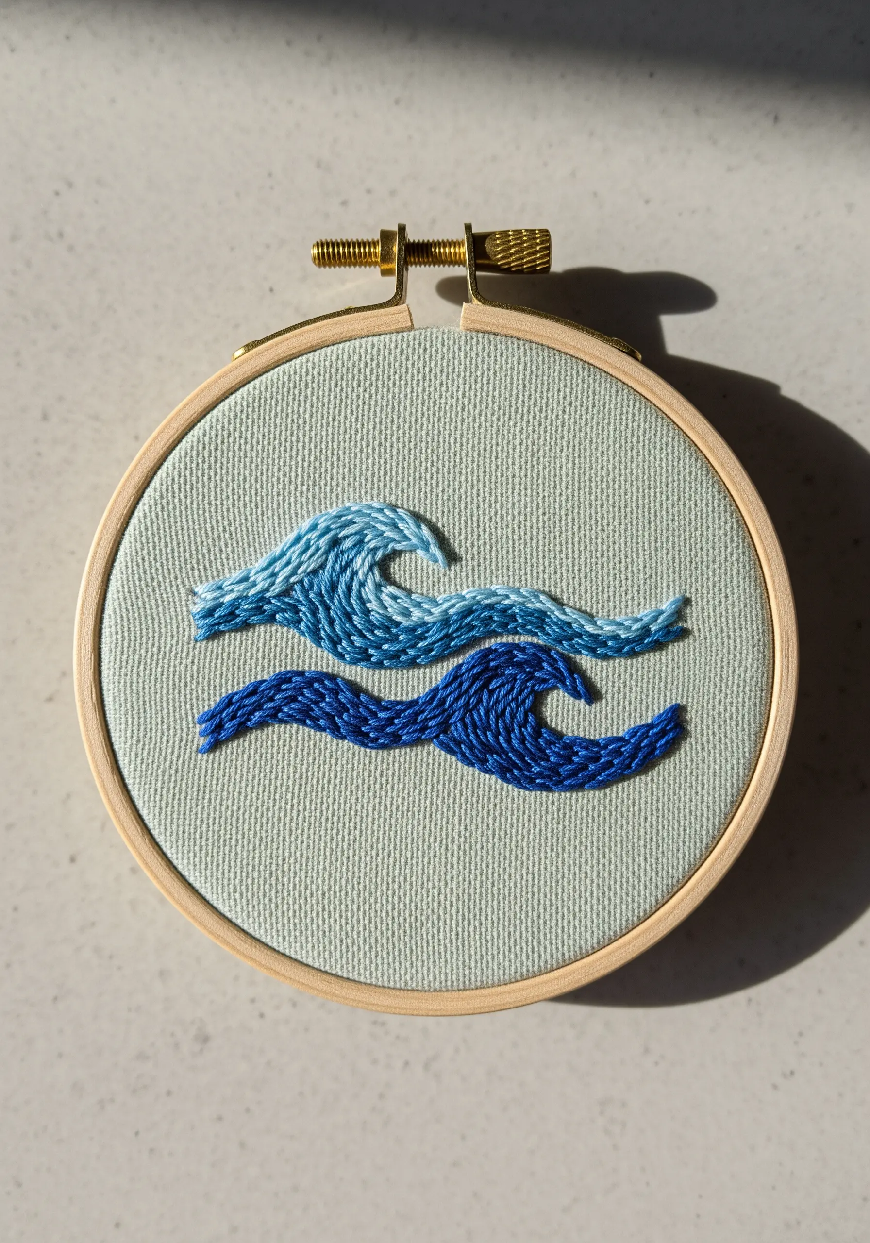 Two stylized waves stitched in different shades of blue using a textured stitch.