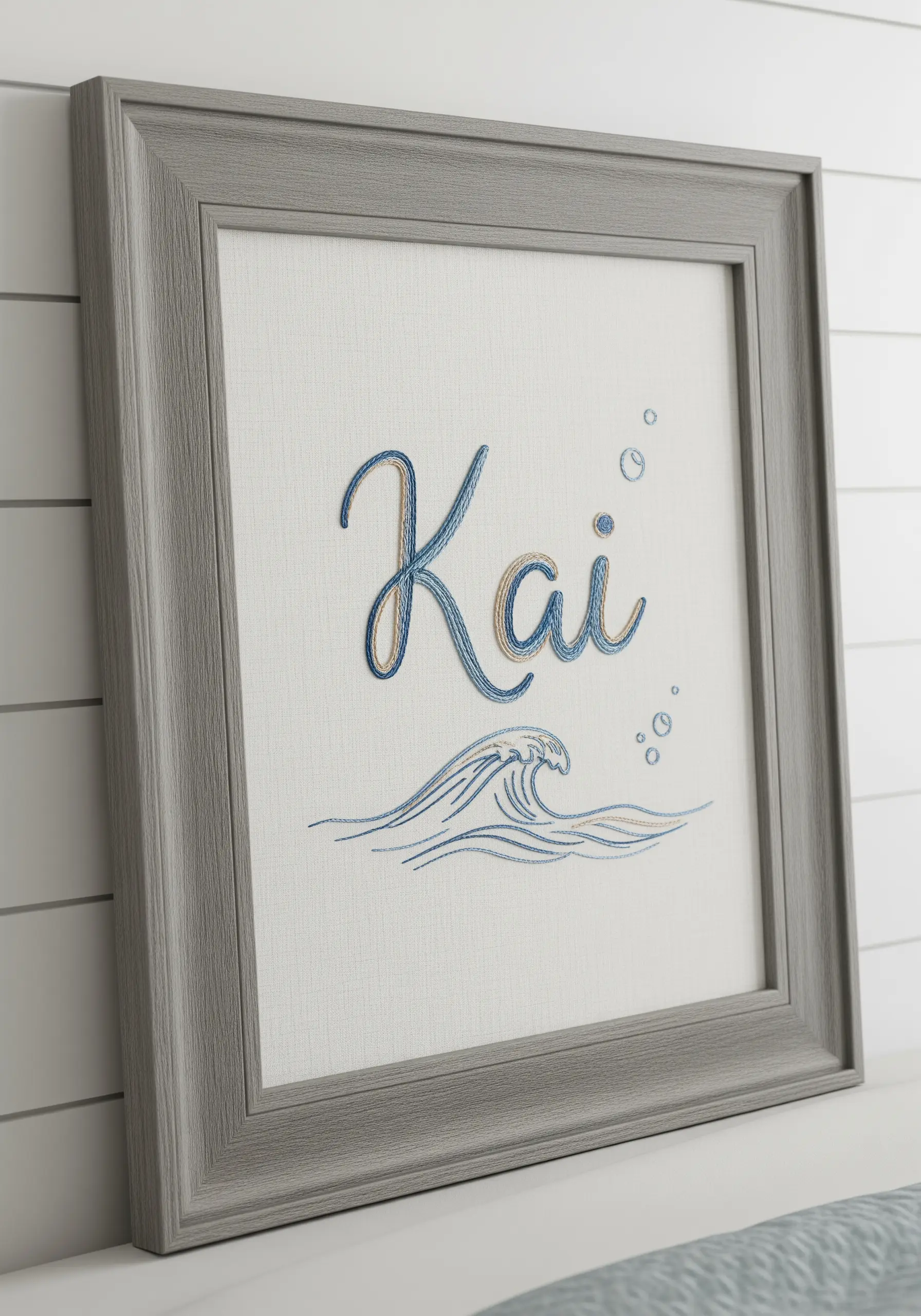 Embroidered name 'Kai' in cursive script above a stylized, stitched ocean wave.