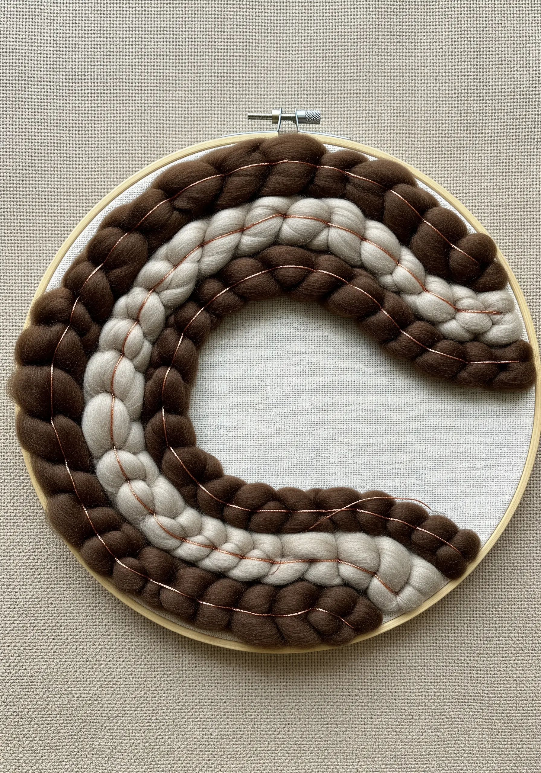 Thick wool roving couched with thin copper wire onto a hoop.