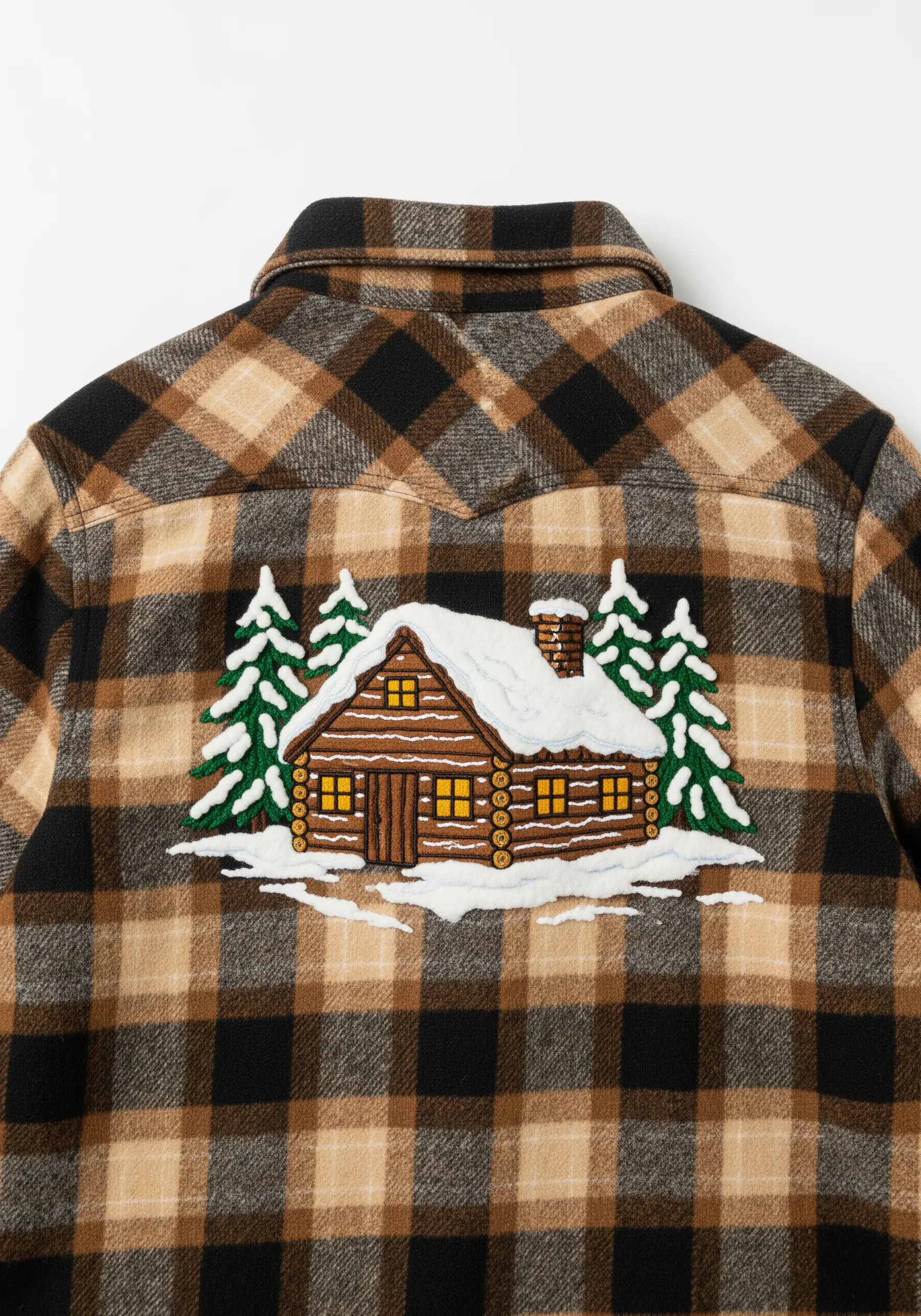 Embroidered snowy log cabin scene on the back of a brown plaid flannel shirt.