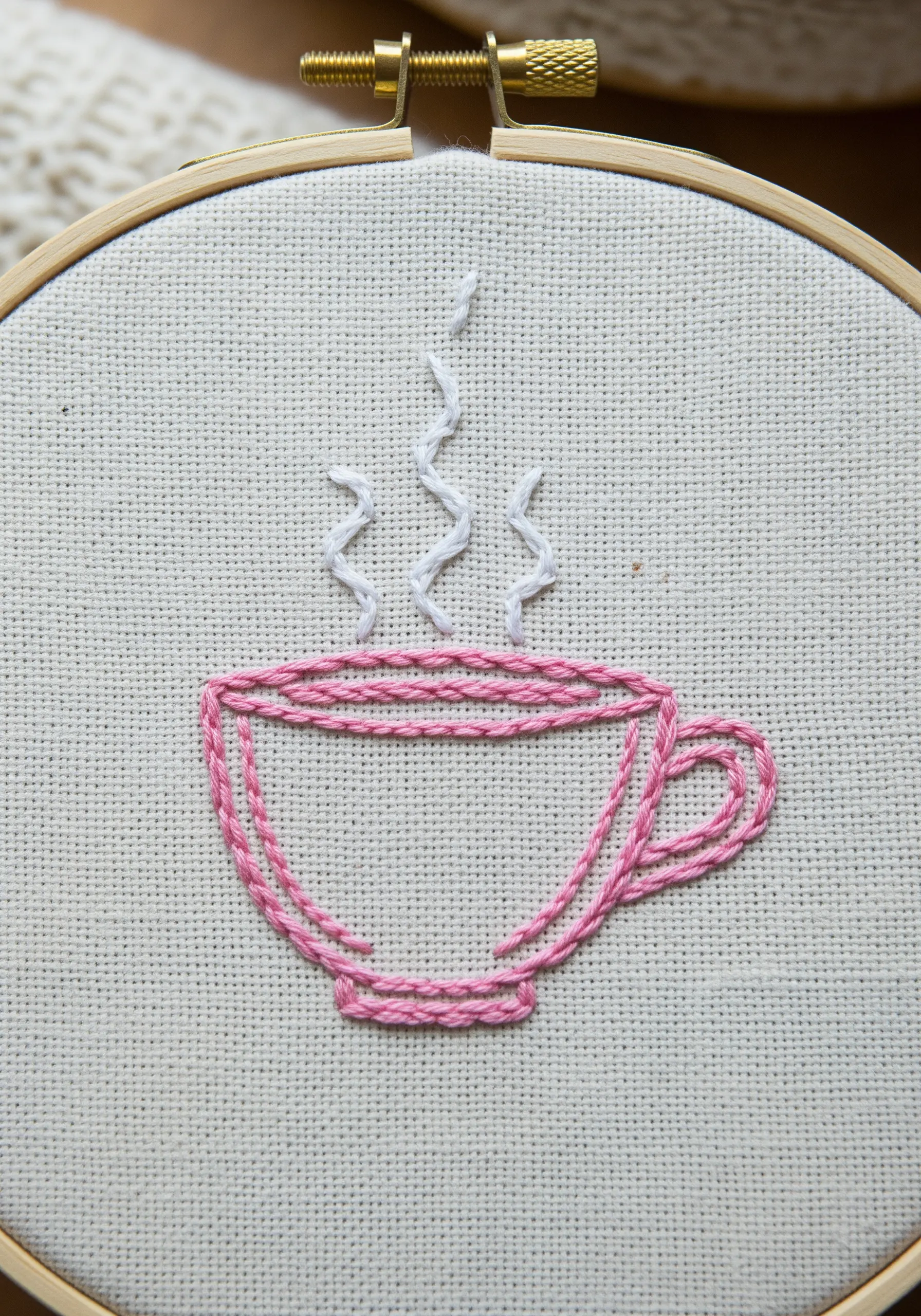 Pink line art teacup with a whipped chain stitch detail and stem stitch steam.