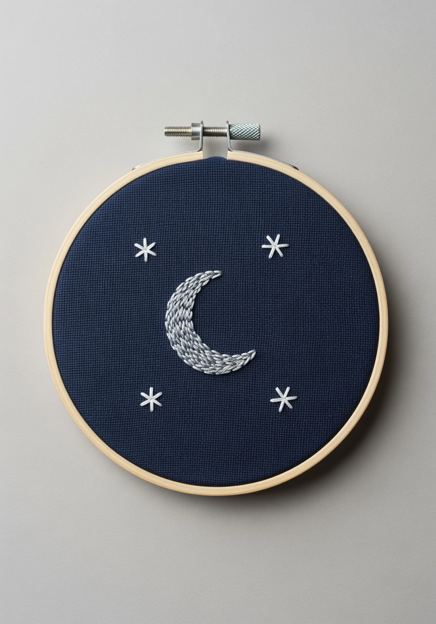 Satin-stitched crescent moon and simple stars on dark navy fabric.