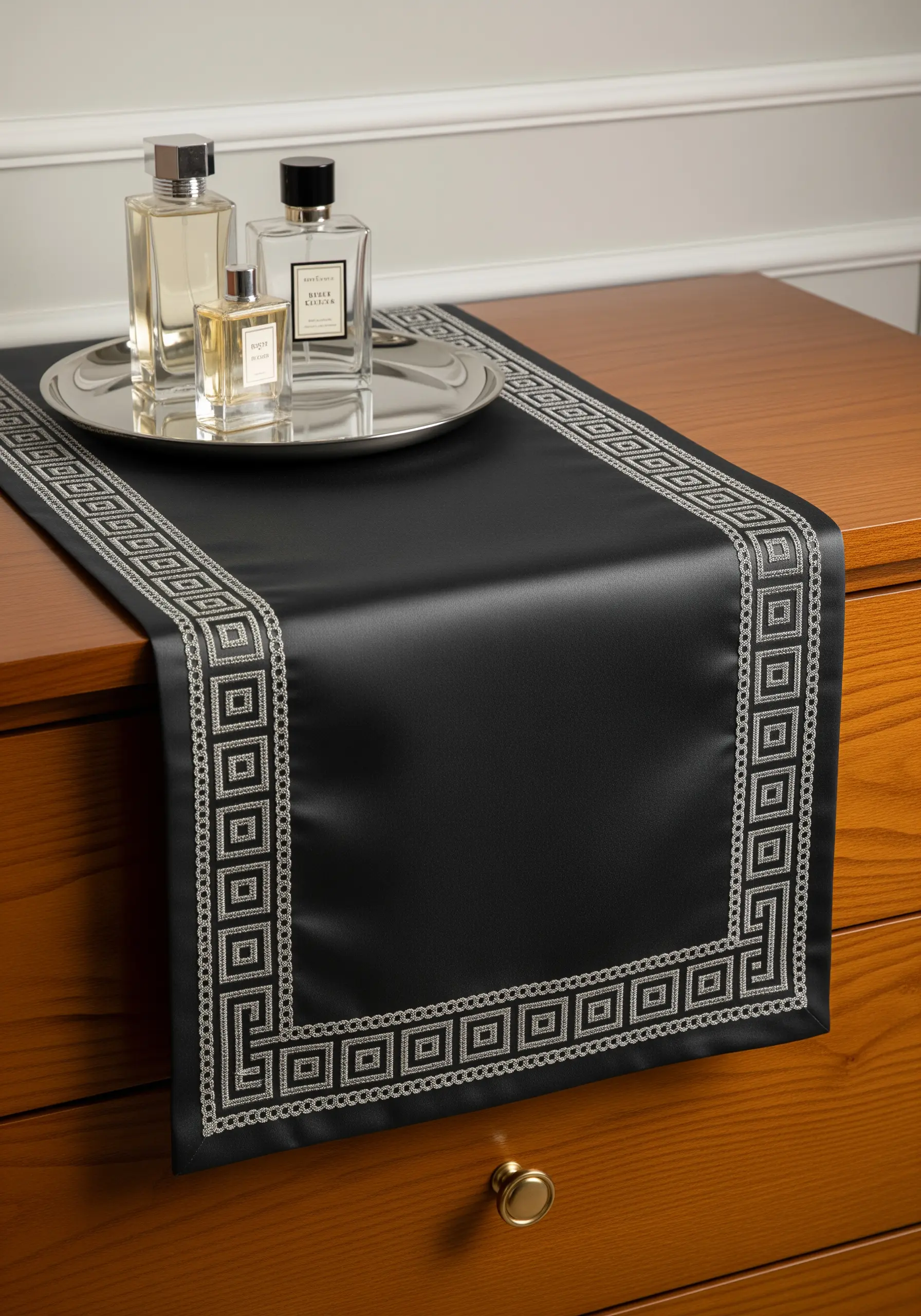 A black satin dresser runner with a sophisticated silver geometric border embroidery.
