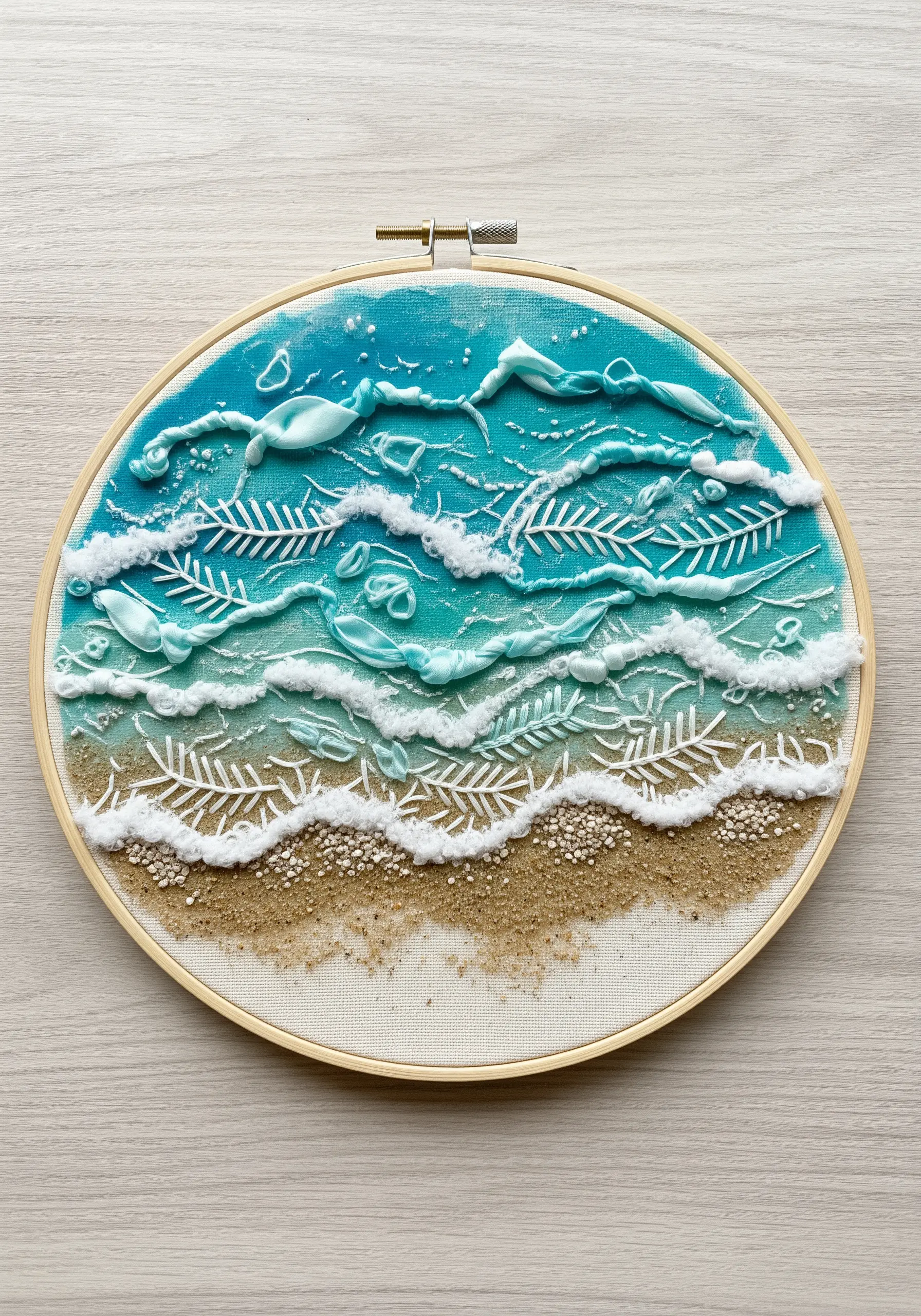 Mixed-media embroidery of a beach with sand, dimensional paint waves, and white stitching.