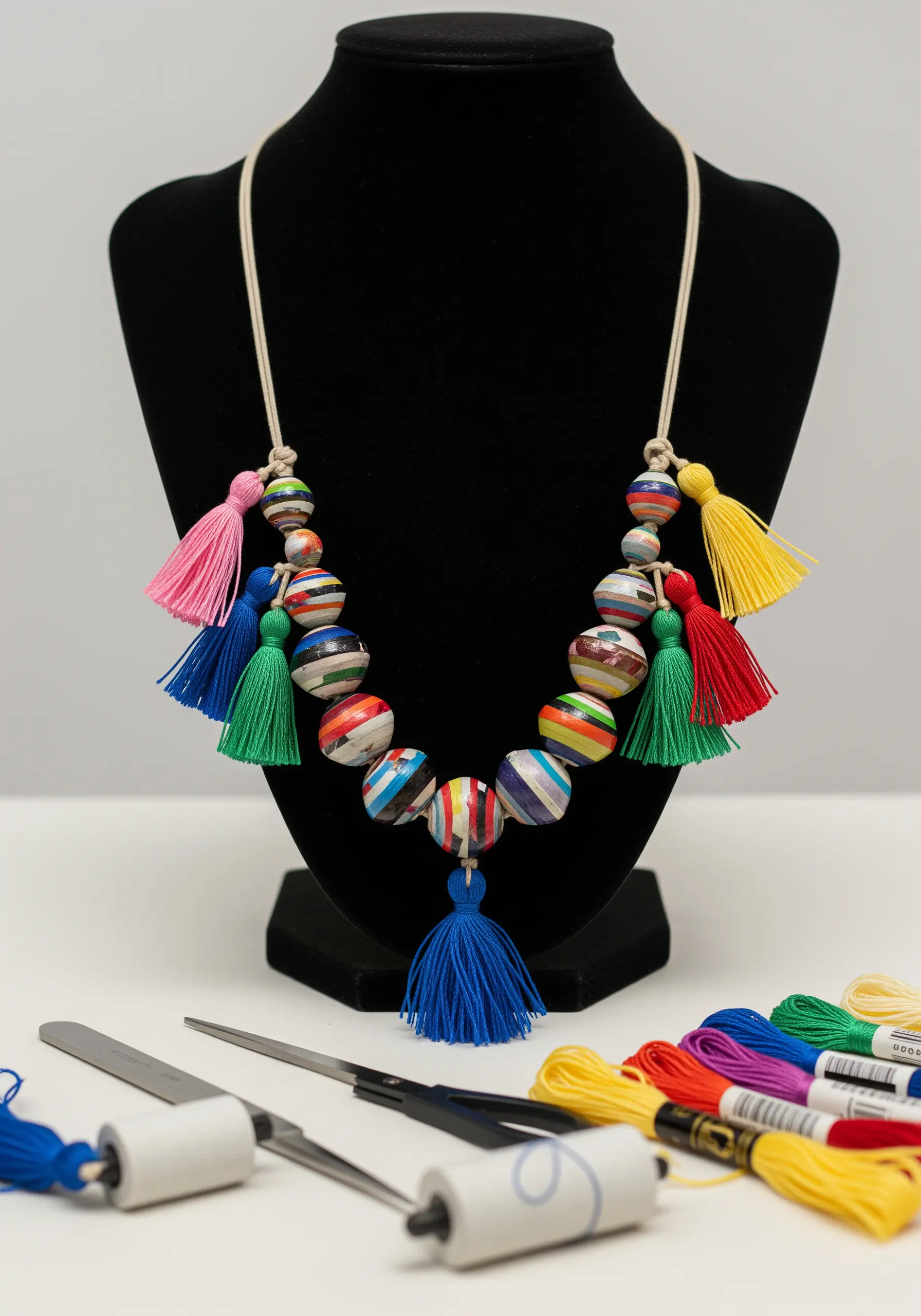A necklace made of colorful rolled paper beads and bright embroidery floss tassels.