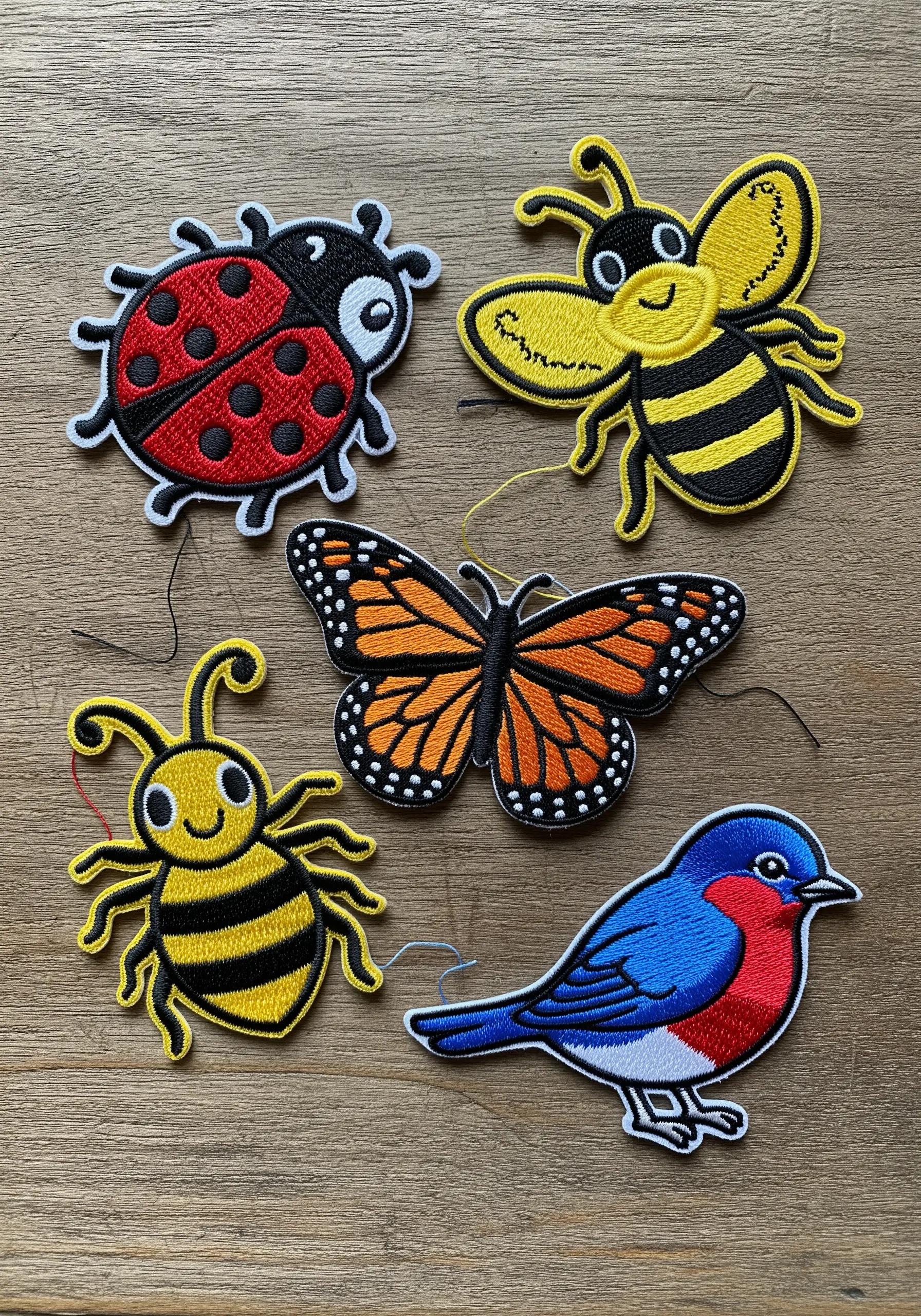 A collection of embroidered patches including bees, a butterfly, a bird, and a ladybug.