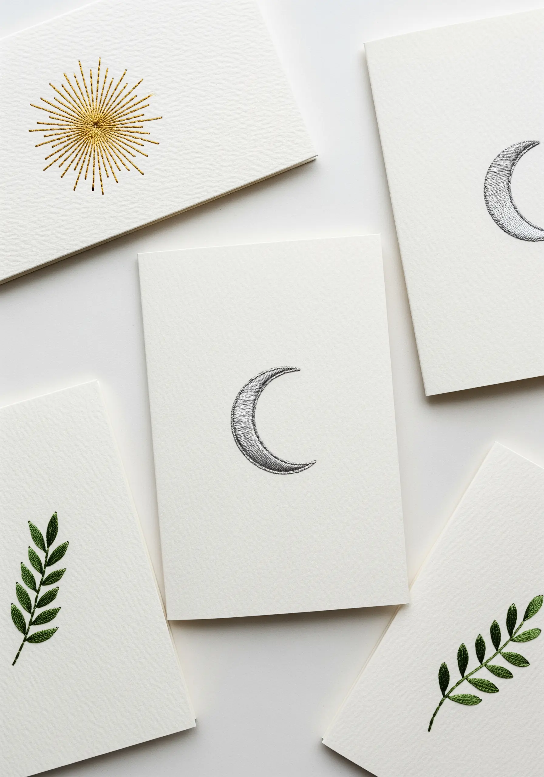 A collection of minimalist greeting cards with small, elegant embroidered motifs like a moon and leaf.