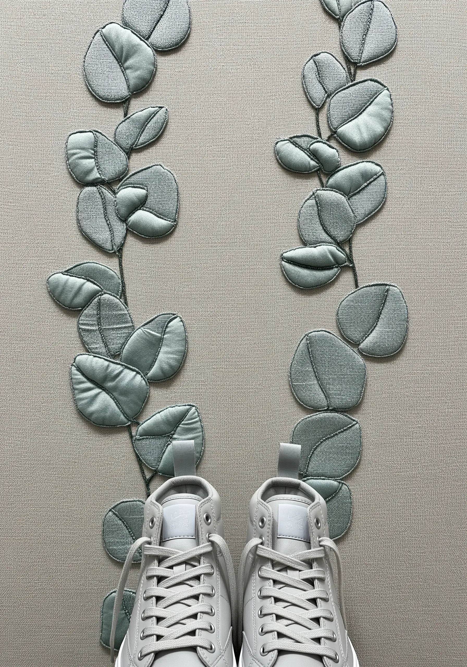 Soft, padded appliqué eucalyptus leaves in sage green stitched onto a neutral background.