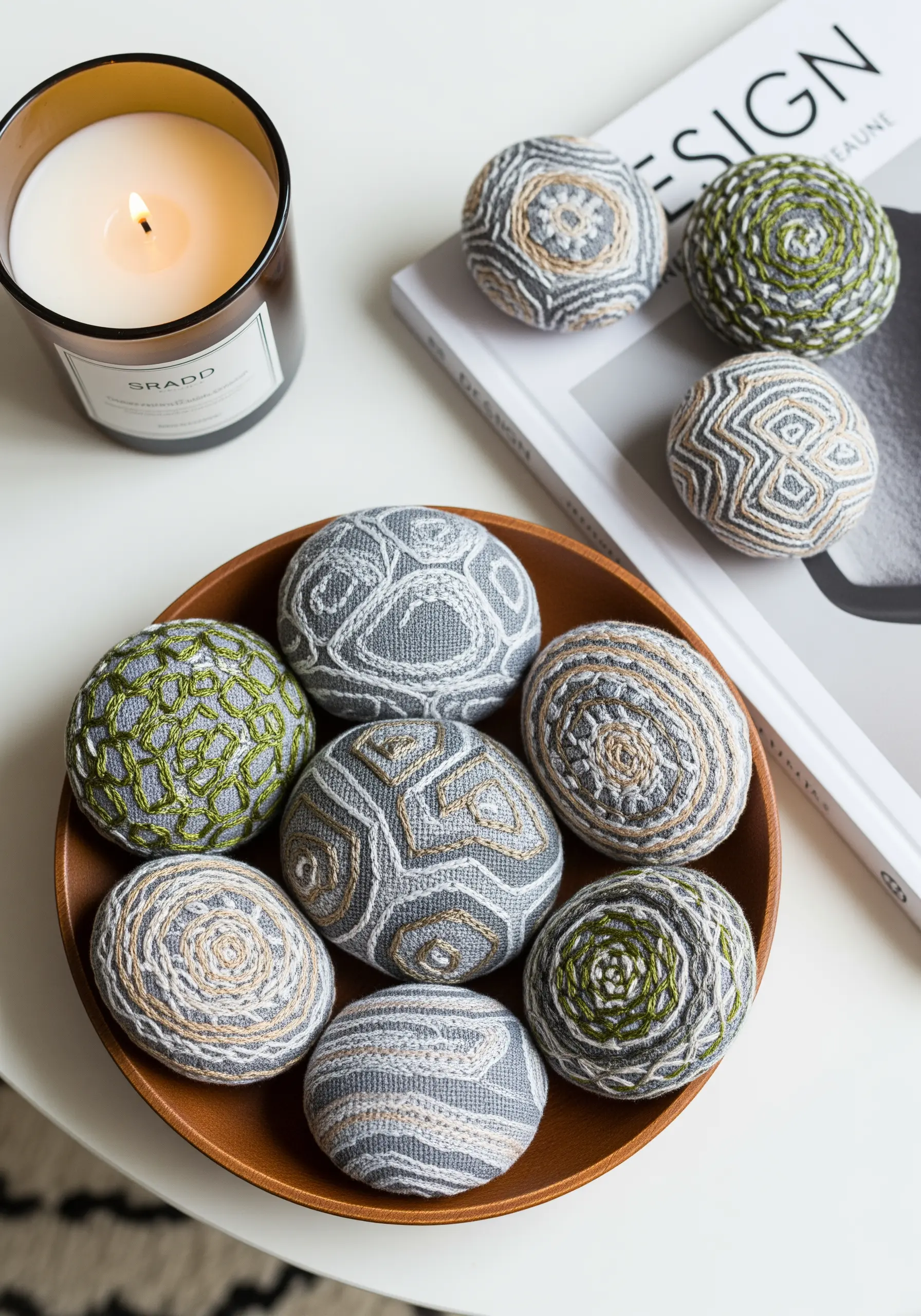 A collection of smooth, round stones wrapped in grey fabric and decorated with embroidered patterns.