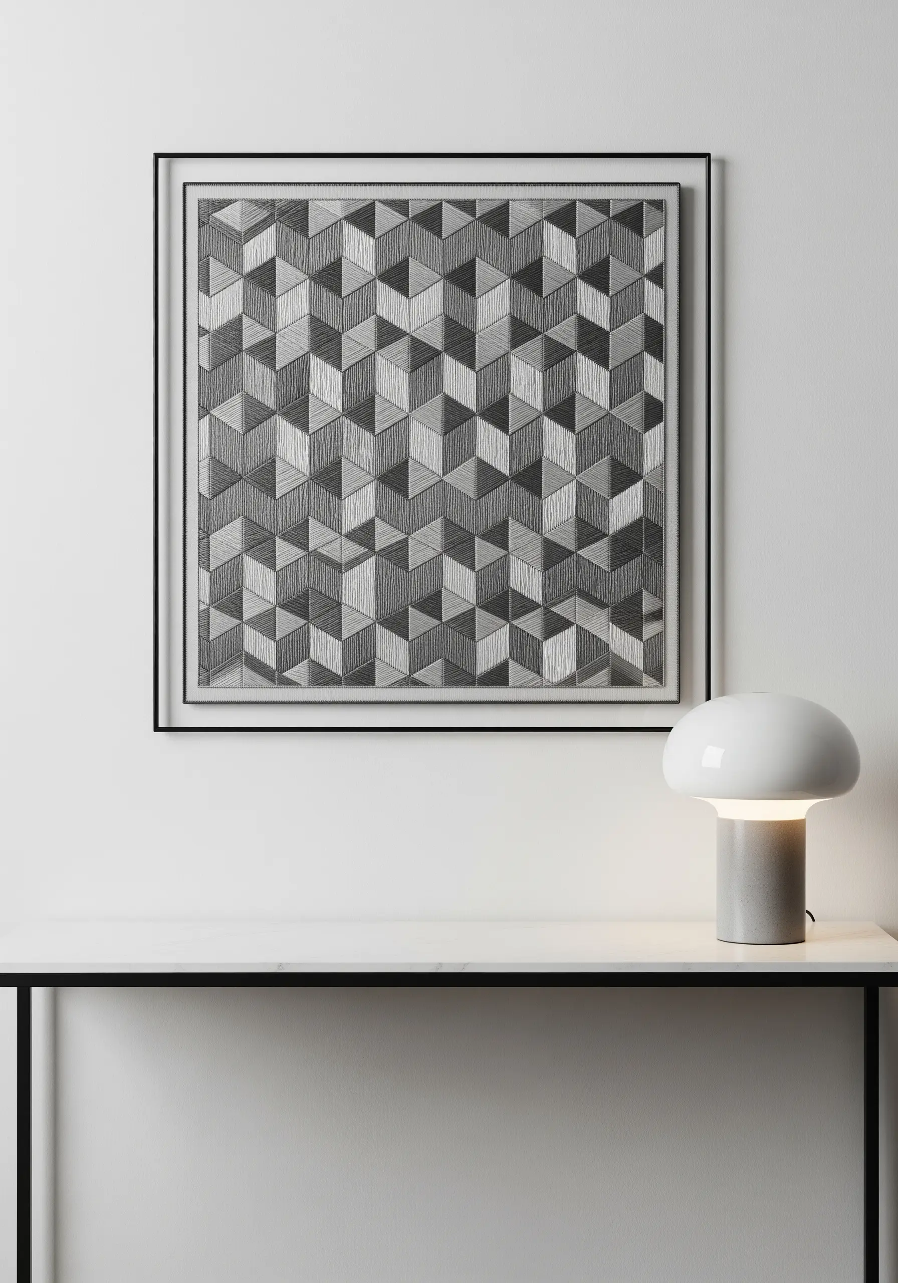 A framed monochrome embroidery featuring a repeating 3D cube pattern creating an optical illusion.
