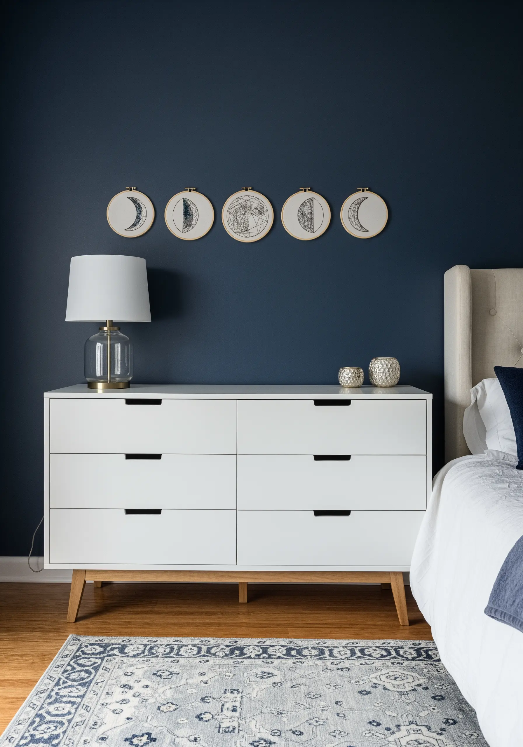 A series of five embroidery hoops showing the phases of the moon, stitched in black thread.