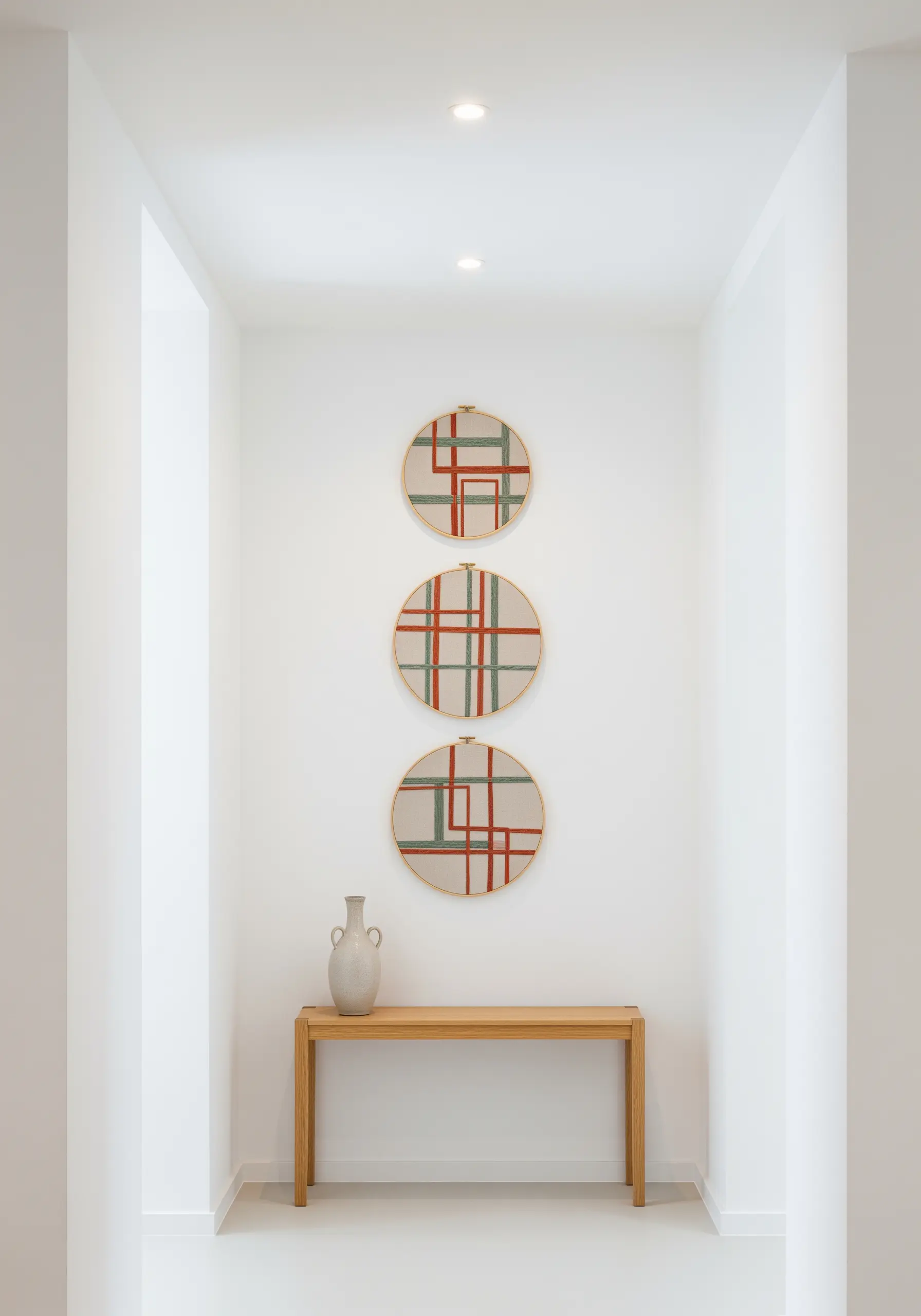 A triptych of embroidery hoops with an abstract red and green grid pattern on a neutral fabric.