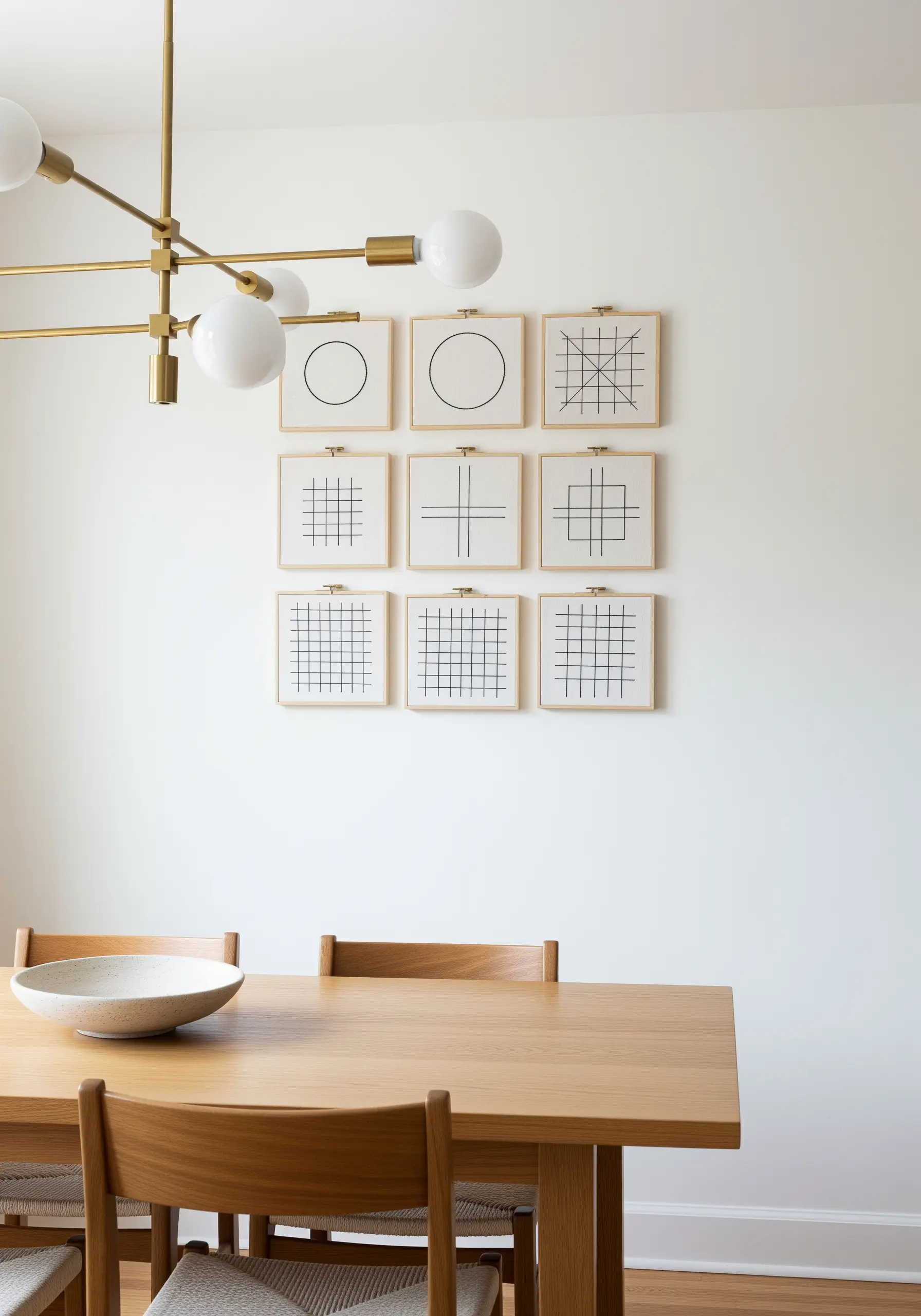 A gallery wall of nine square embroidery hoops, each with a minimalist geometric line design.