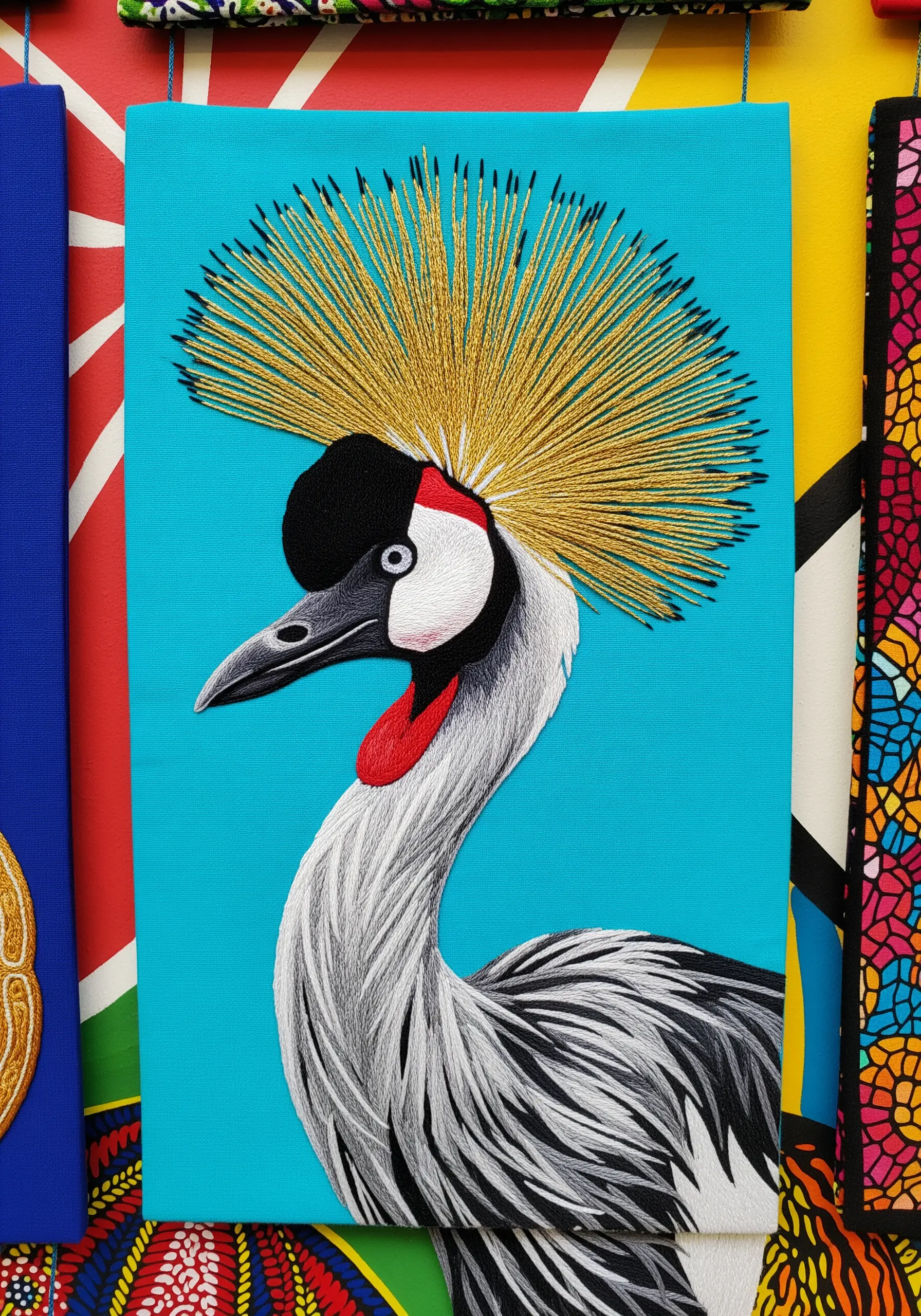 Embroidered crowned crane with a dramatic crown of radiating gold stitches.