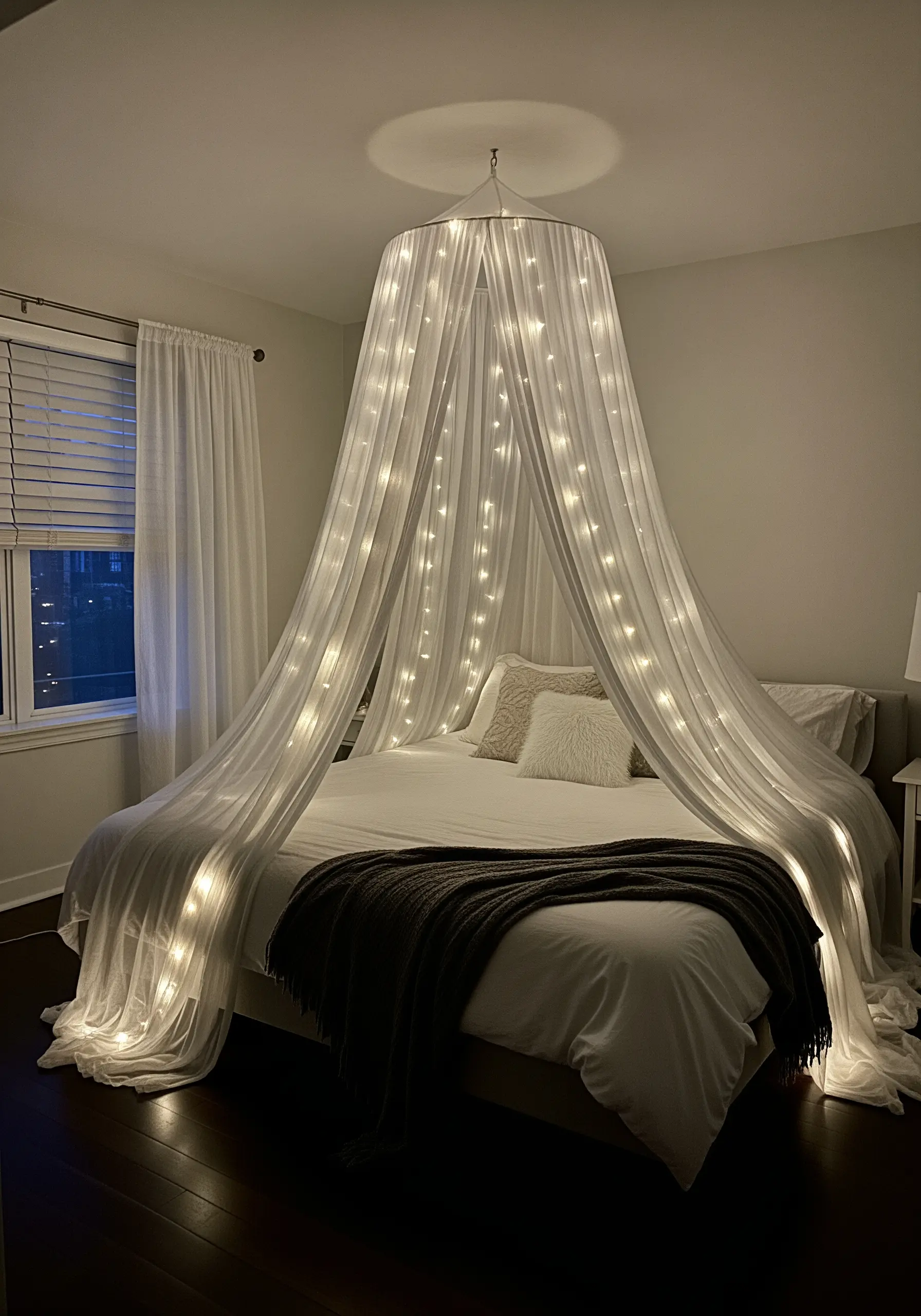 A bed with a sheer white canopy illuminated by strings of warm fairy lights.
