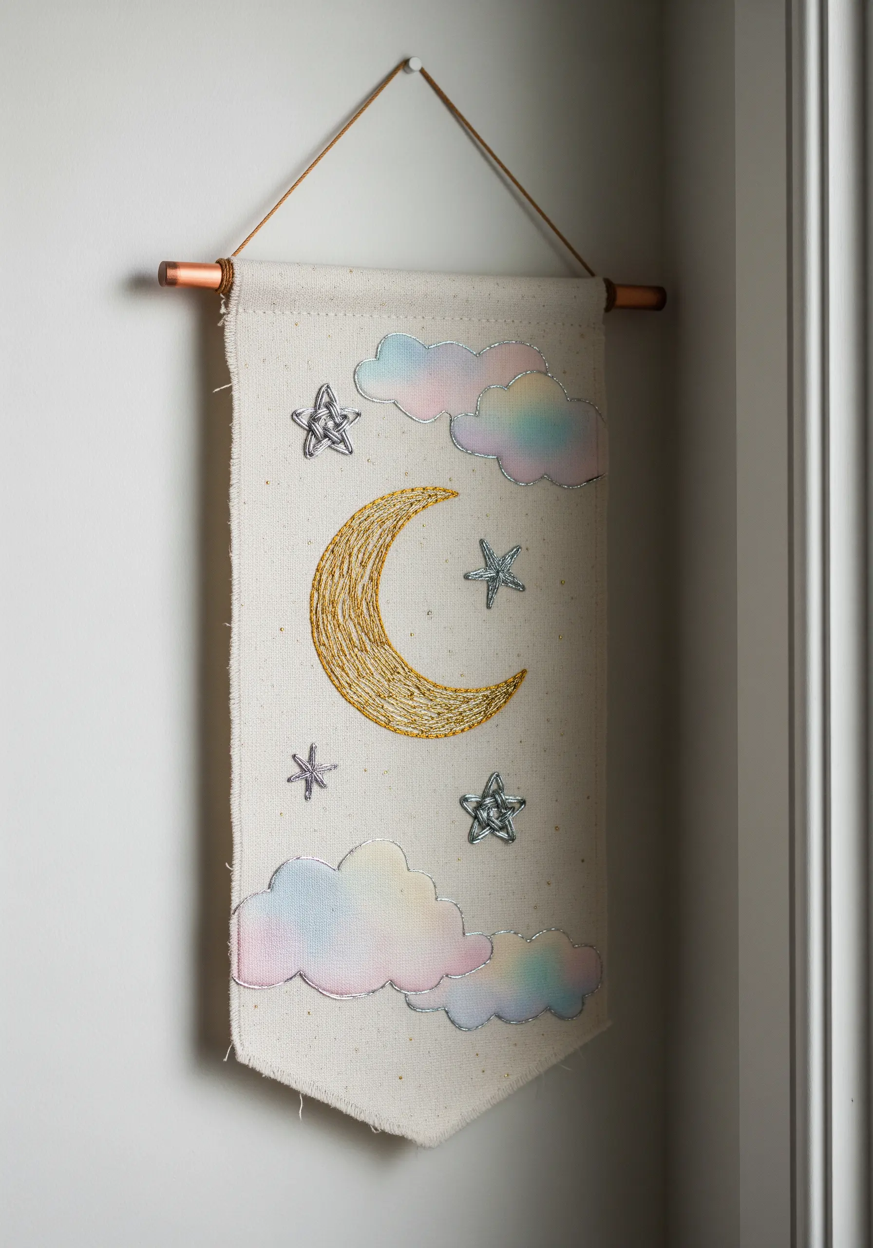 A celestial wall hanging with a metallic thread moon and watercolor-tinted clouds.