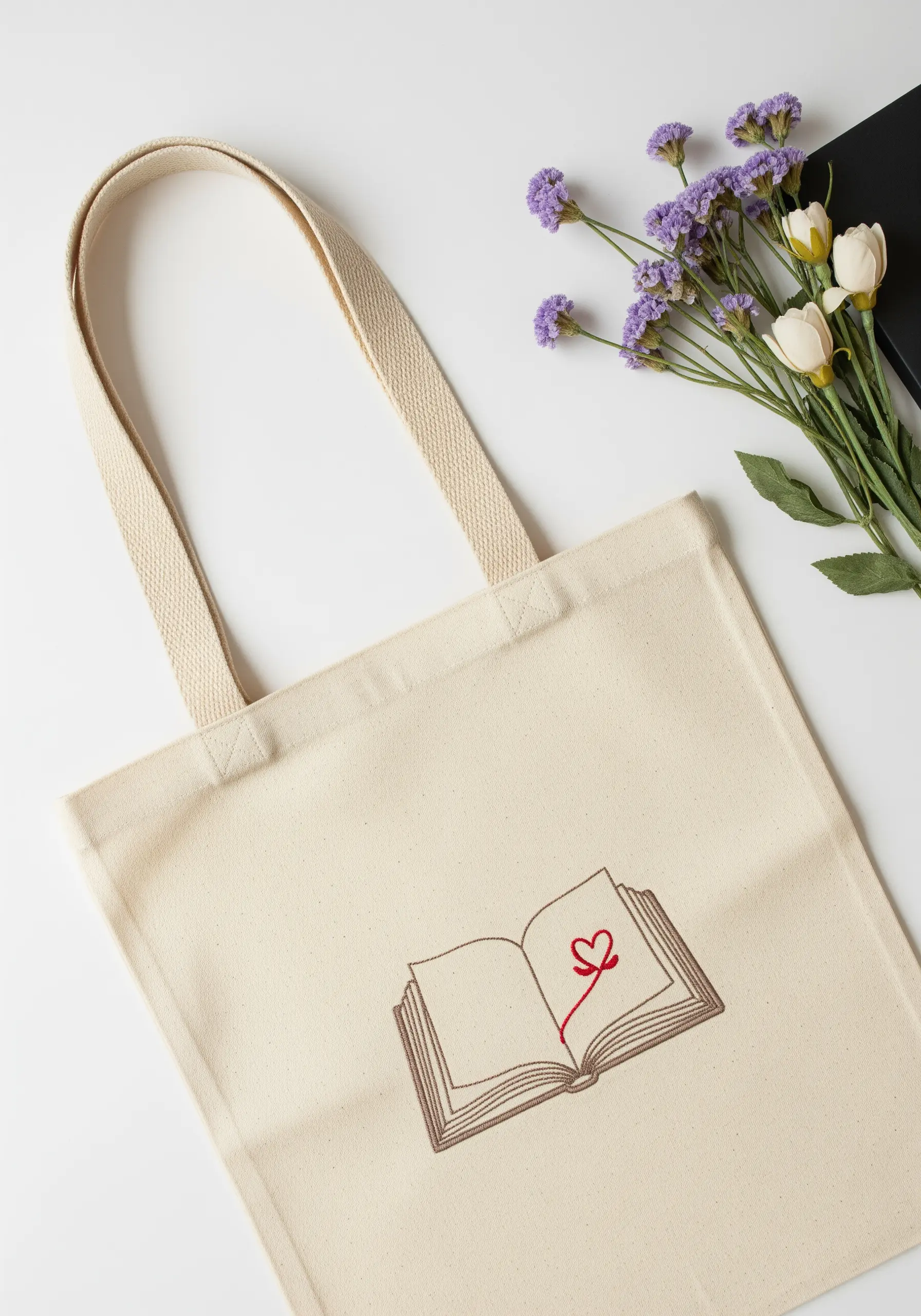 An outline of an open book on a tote bag with a small, bright red heart in the center.