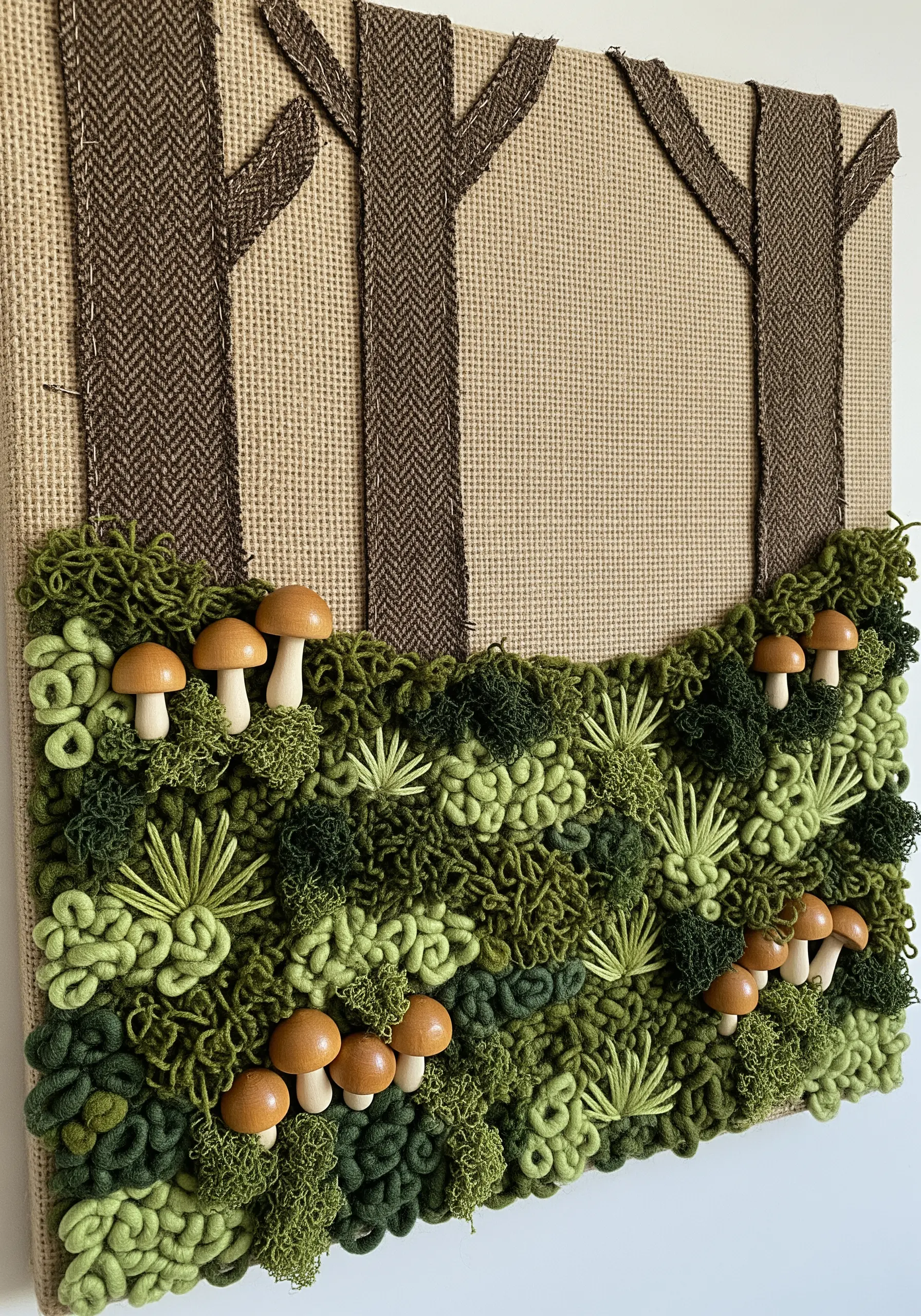 A textured forest scene with yarn moss, wooden mushrooms, and fabric appliqué trees.