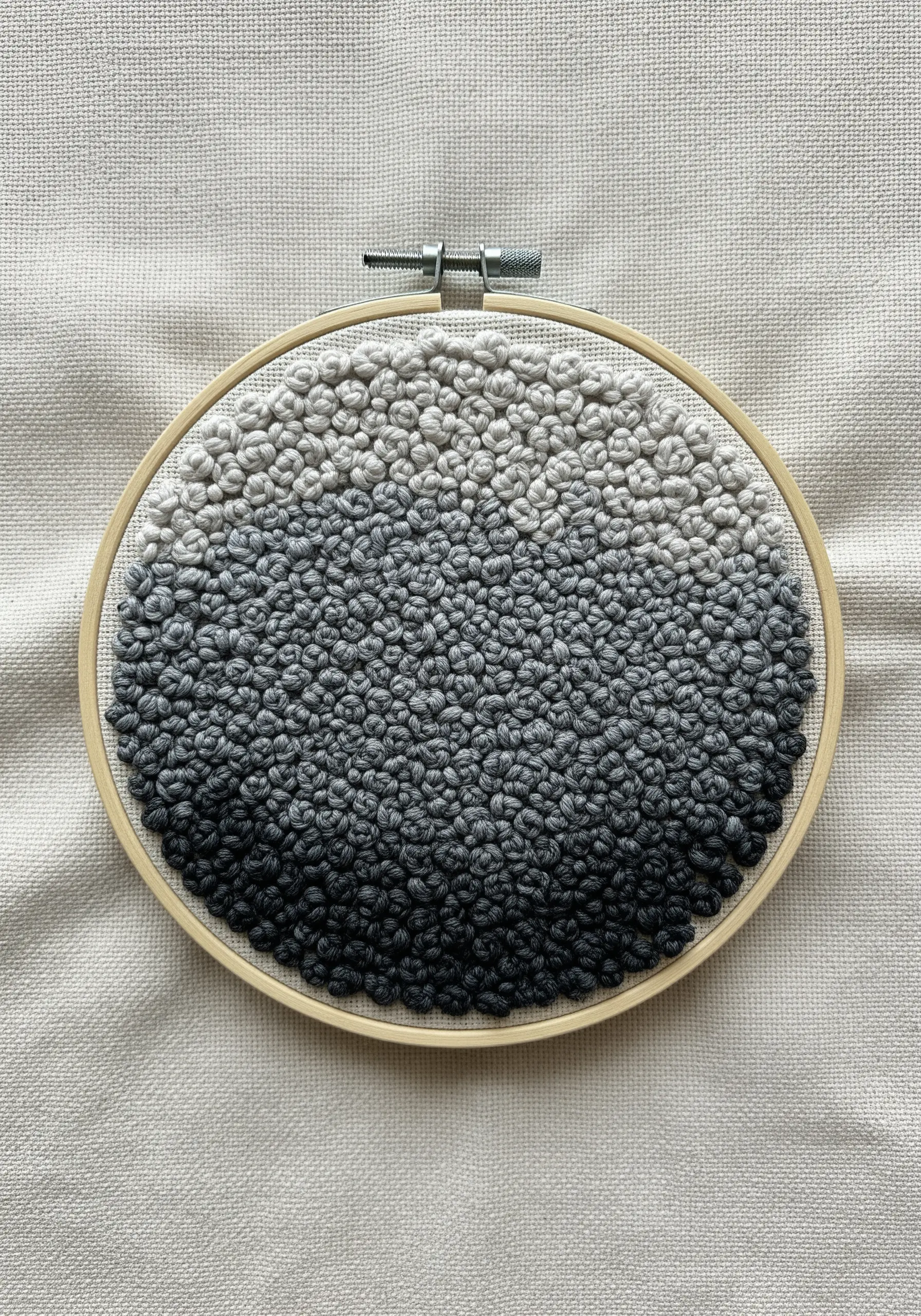 A circle filled with French knots transitioning from black to white.