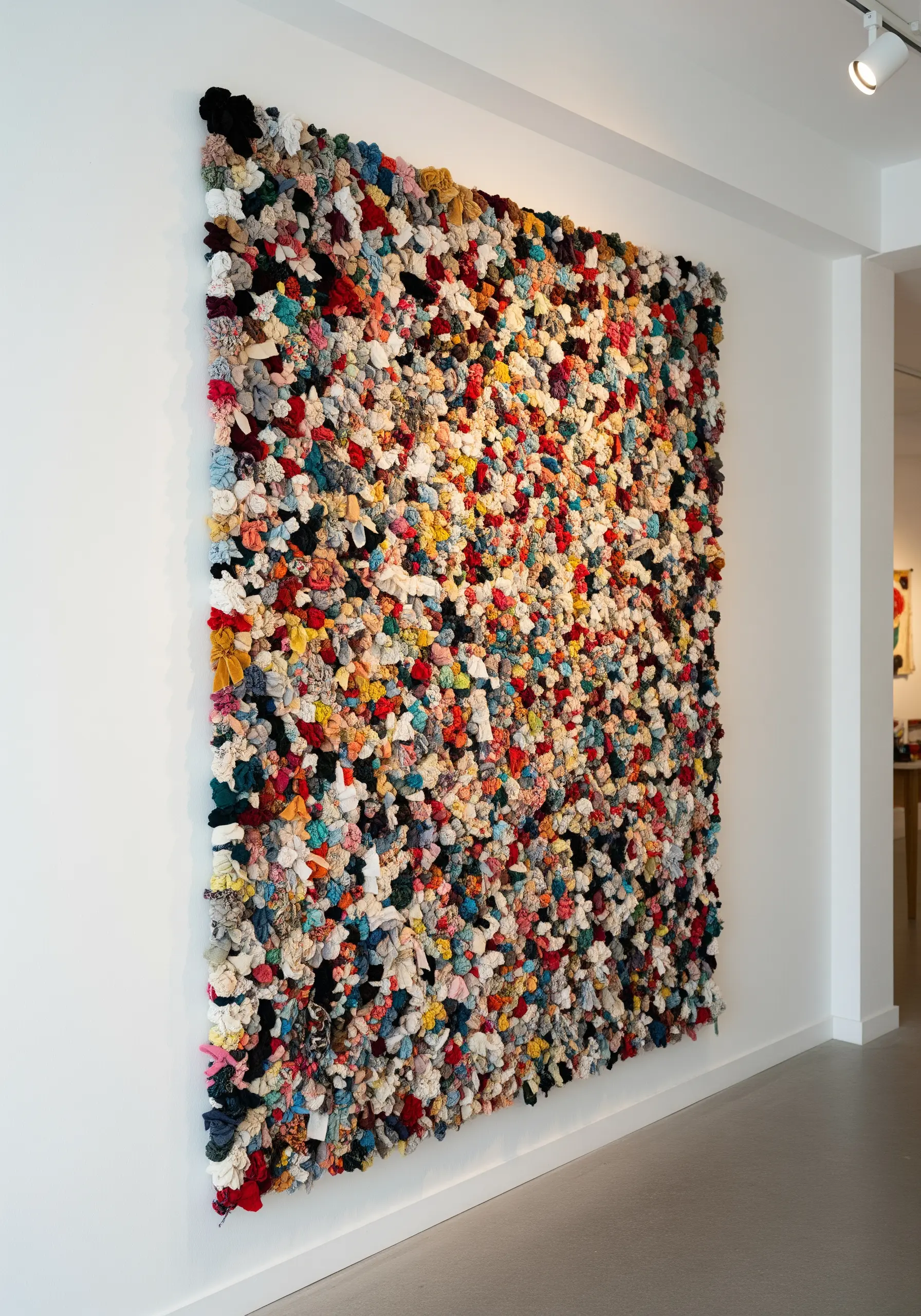 Large-scale wall art made from a dense collage of colorful fabric scraps.