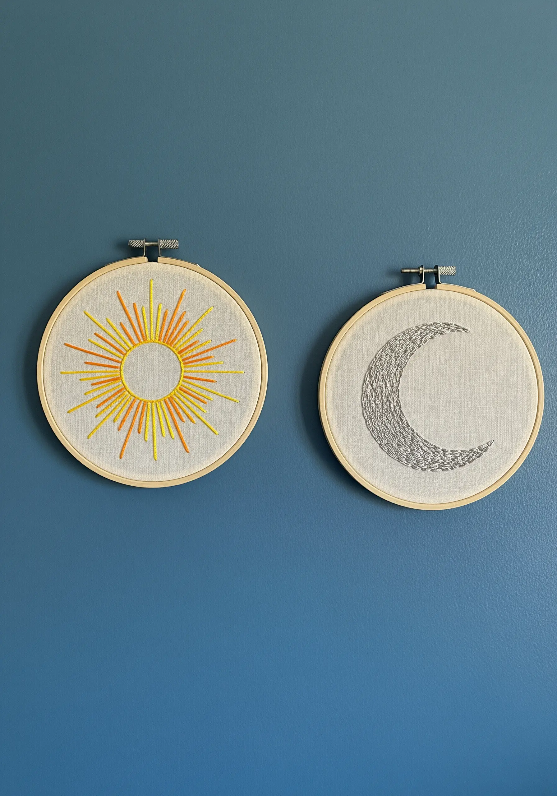 Two embroidery hoops displayed together, one with a sun and one with a moon.