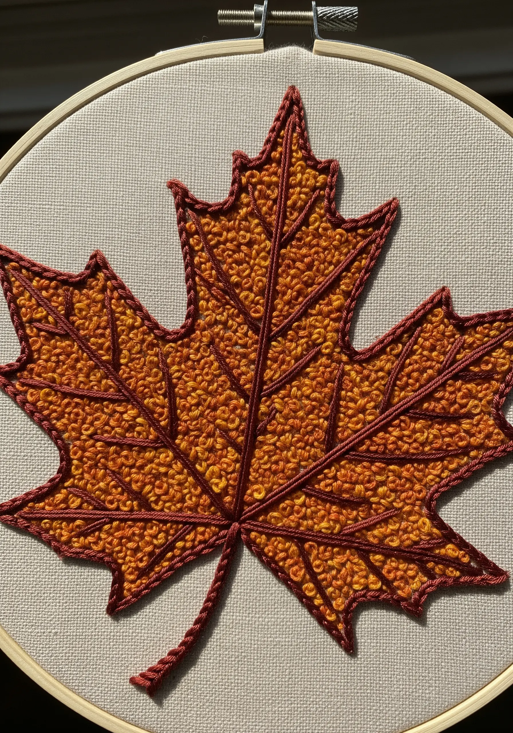 Orange maple leaf with French knot texture and raised, dark red veins.