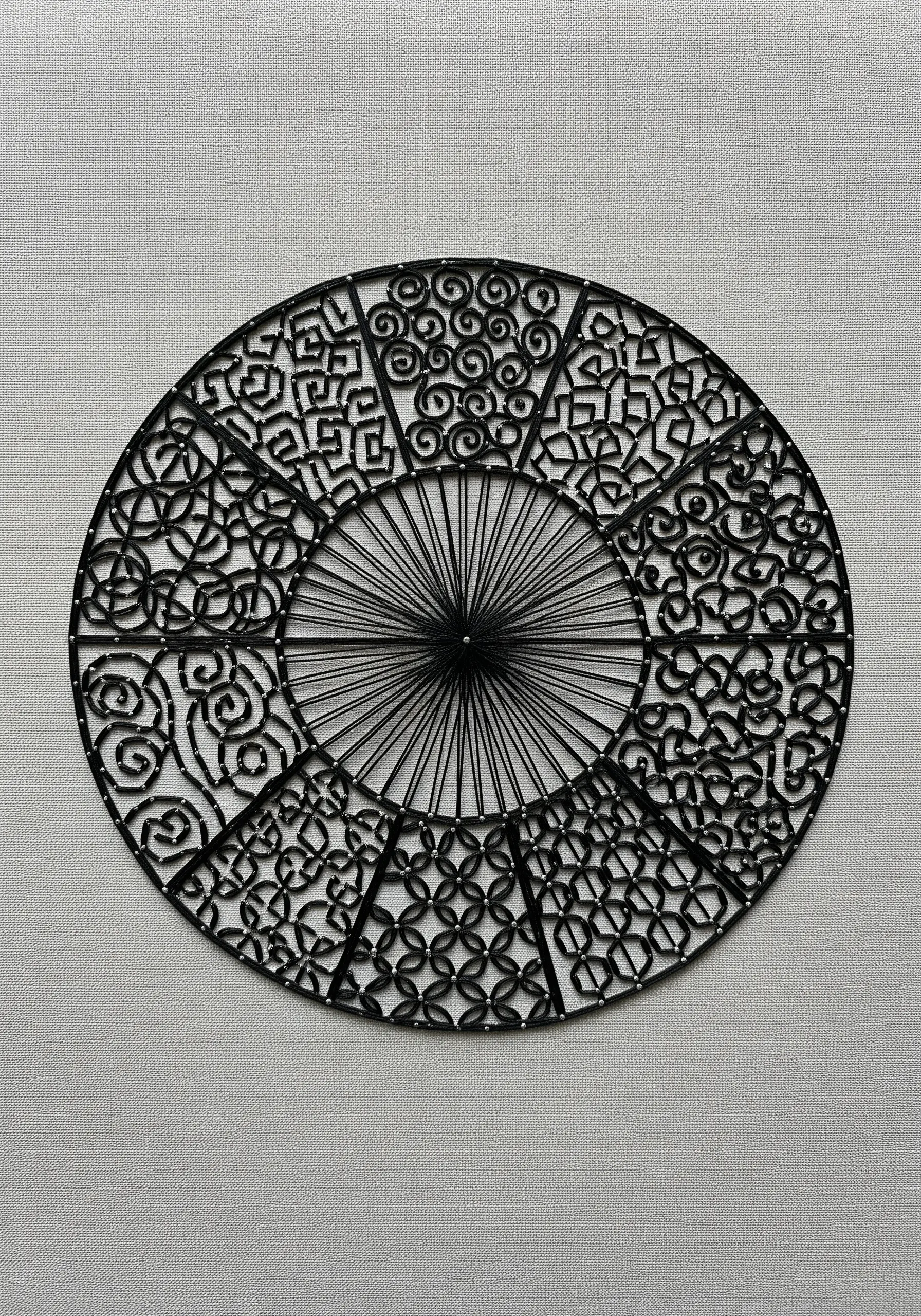 A black string art mandala with different geometric patterns in each segment.