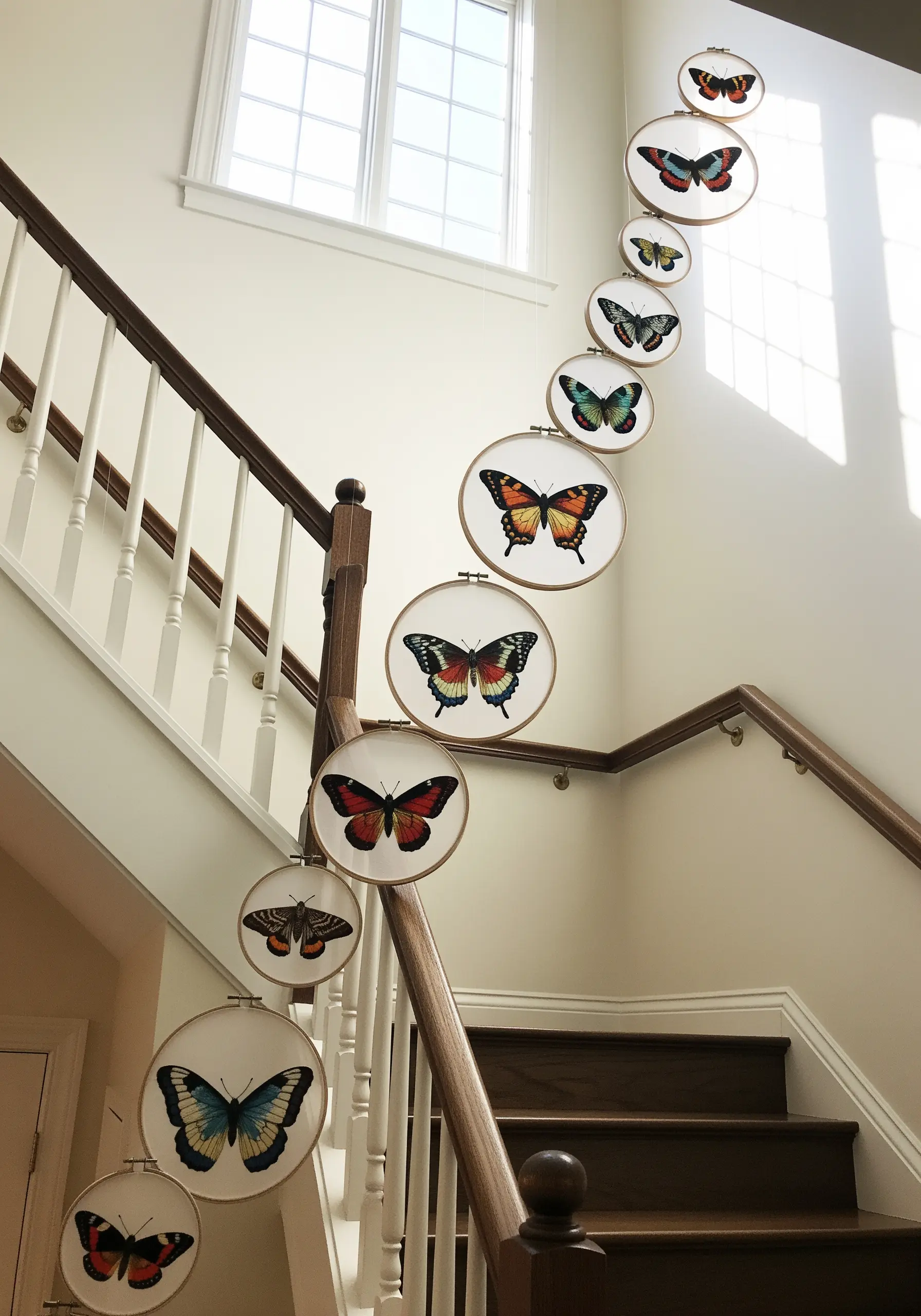 A hanging installation of embroidered butterfly hoops cascading down a staircase.