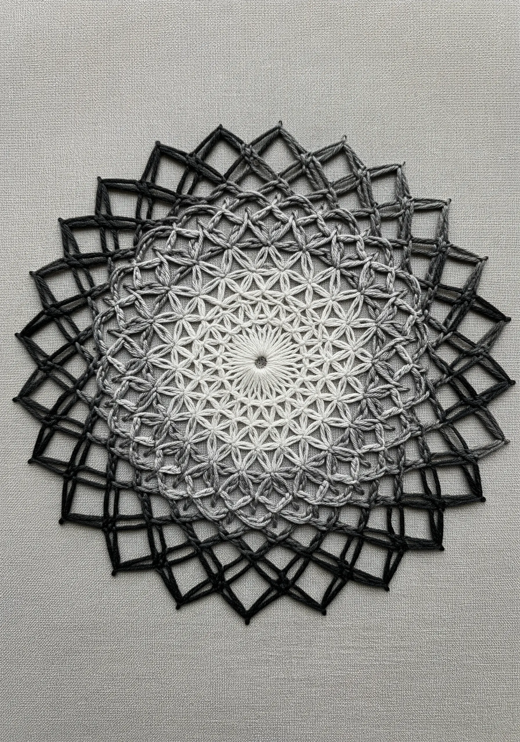 A Flower of Life mandala embroidered with a smooth gradient from white to black.