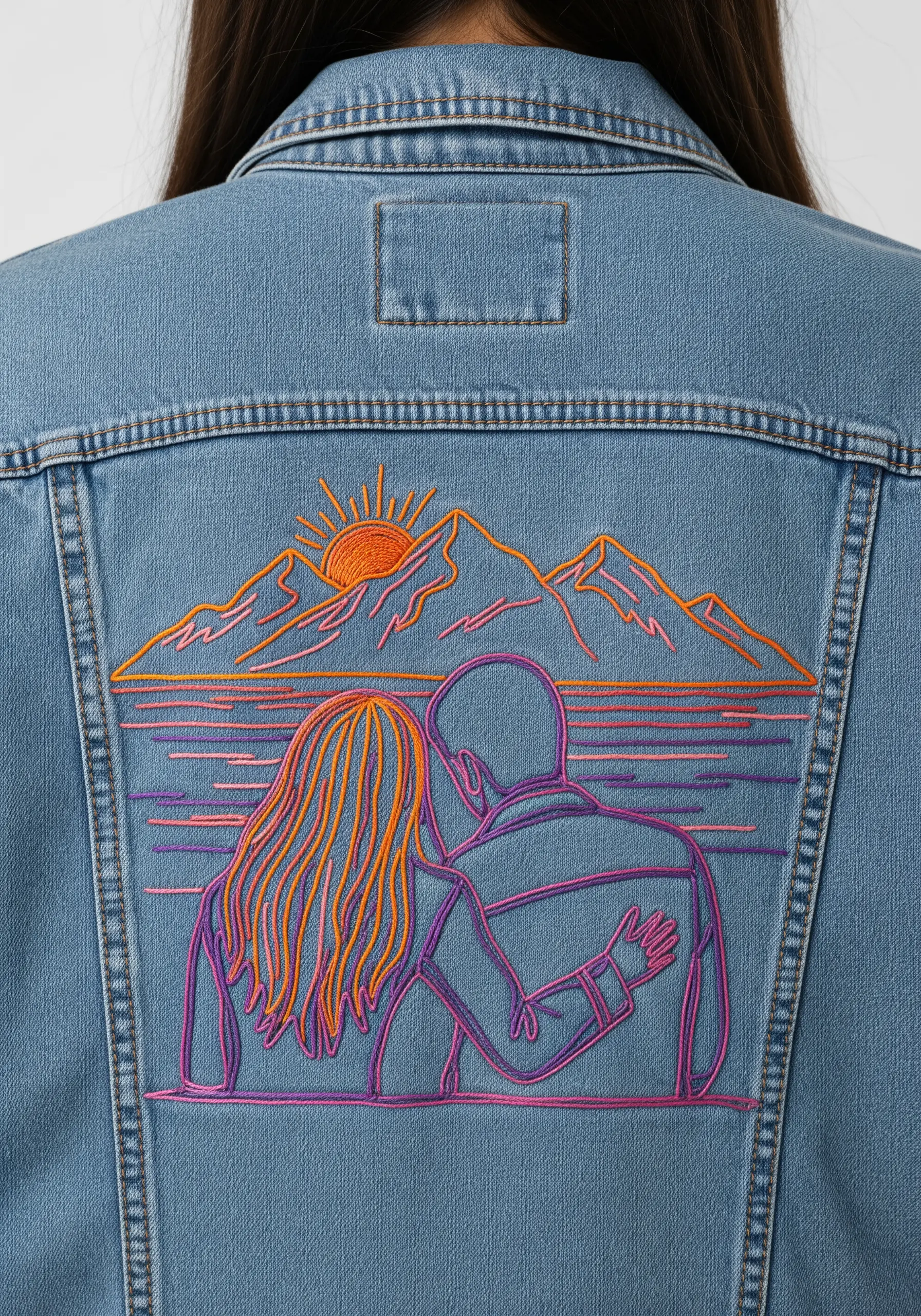 Embroidered couple watching a sunset on the back of a denim jacket, with vibrant thread colors.