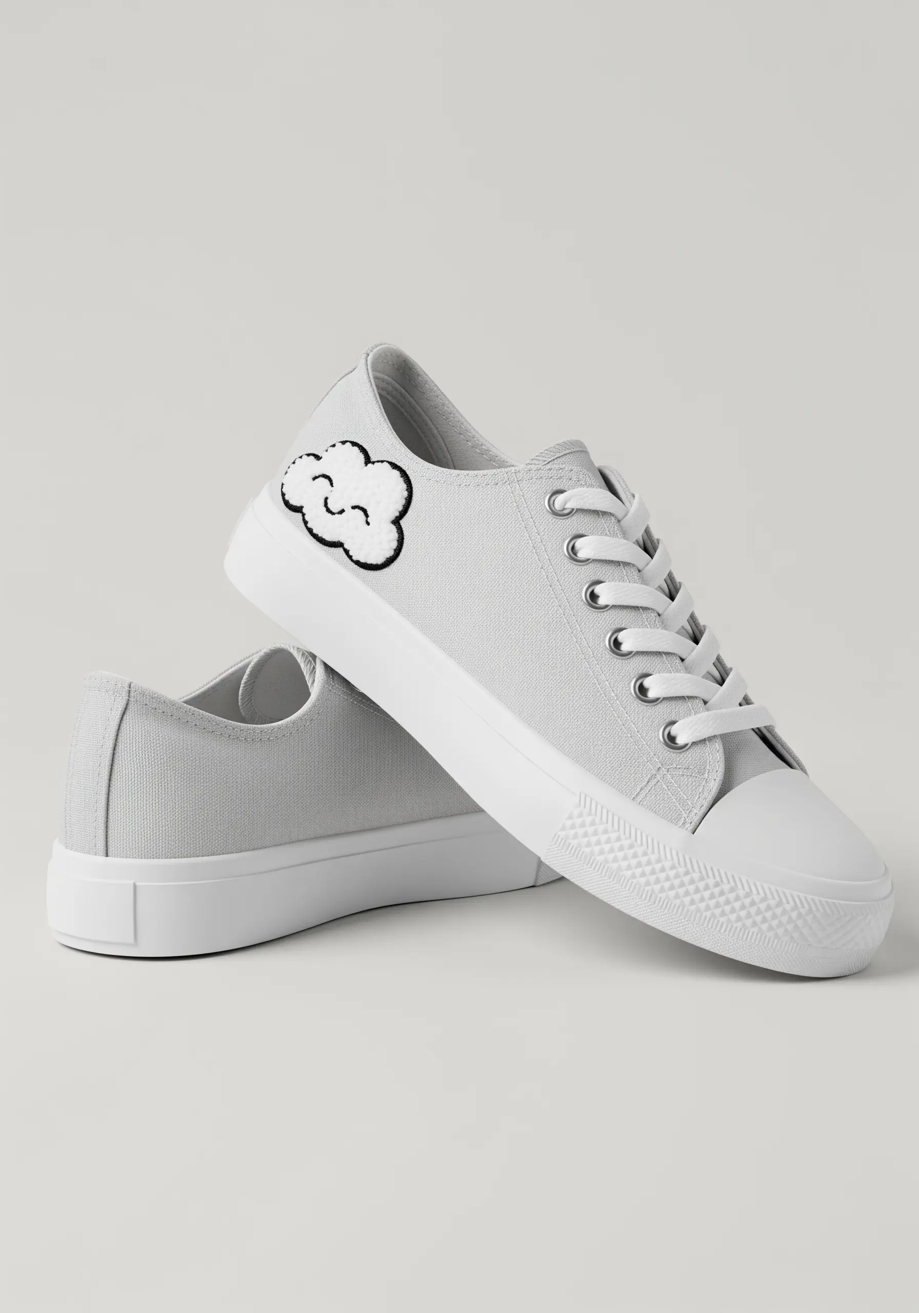 A small, smiling cloud patch with a black outline embroidered on a white canvas sneaker.