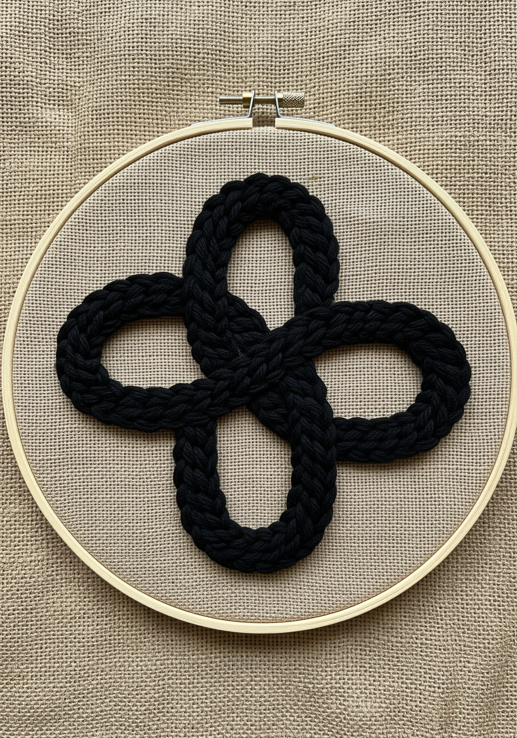 Thick, raised embroidery of a Celtic knot on coarse burlap fabric.