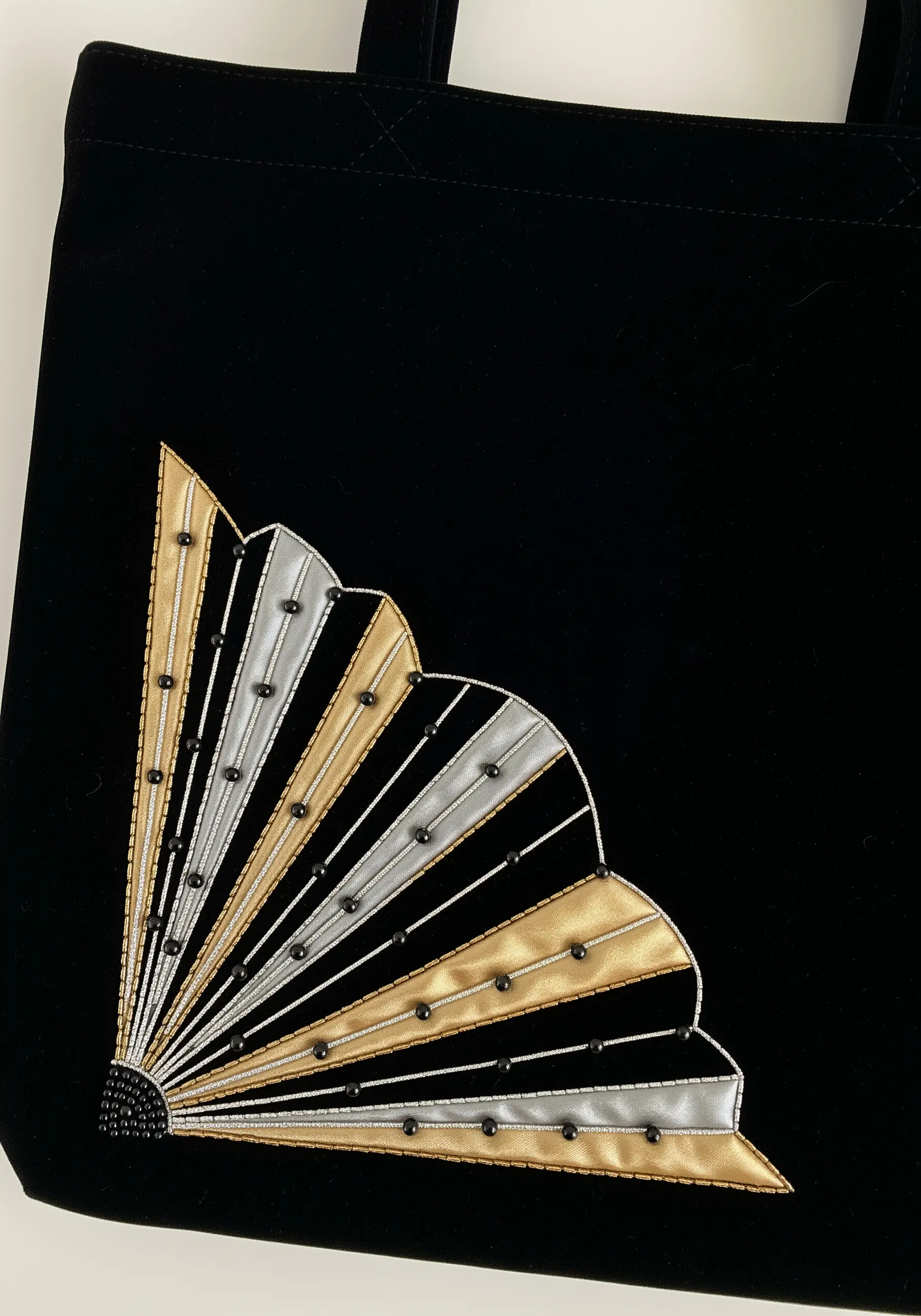 An Art Deco fan design in gold and silver satin stitch with black beads on a black velvet tote.