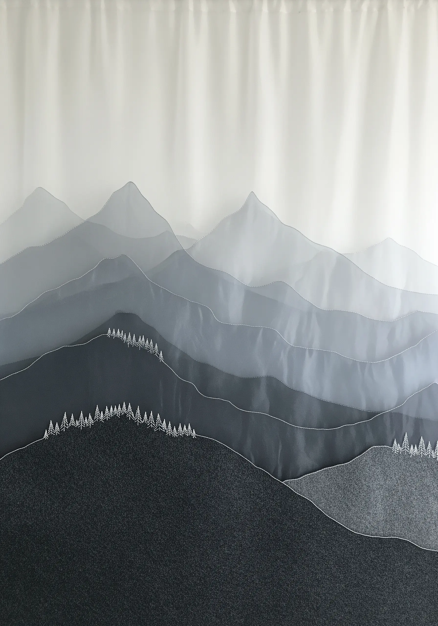 A mountain landscape created with layers of sheer gray fabric and minimal white stitching.