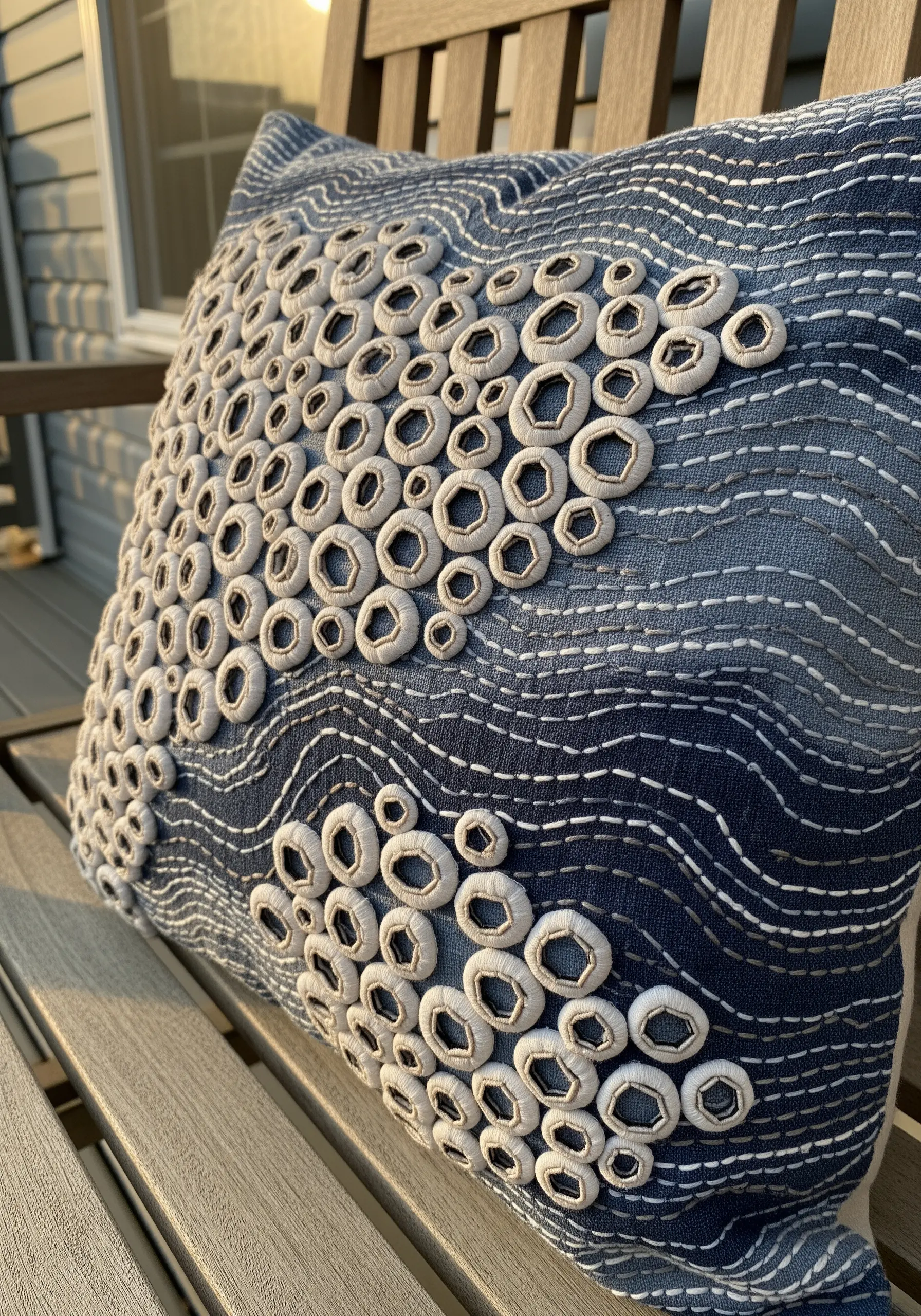 Close-up of a blue cushion with raised, embroidered white rings that look like barnacles.
